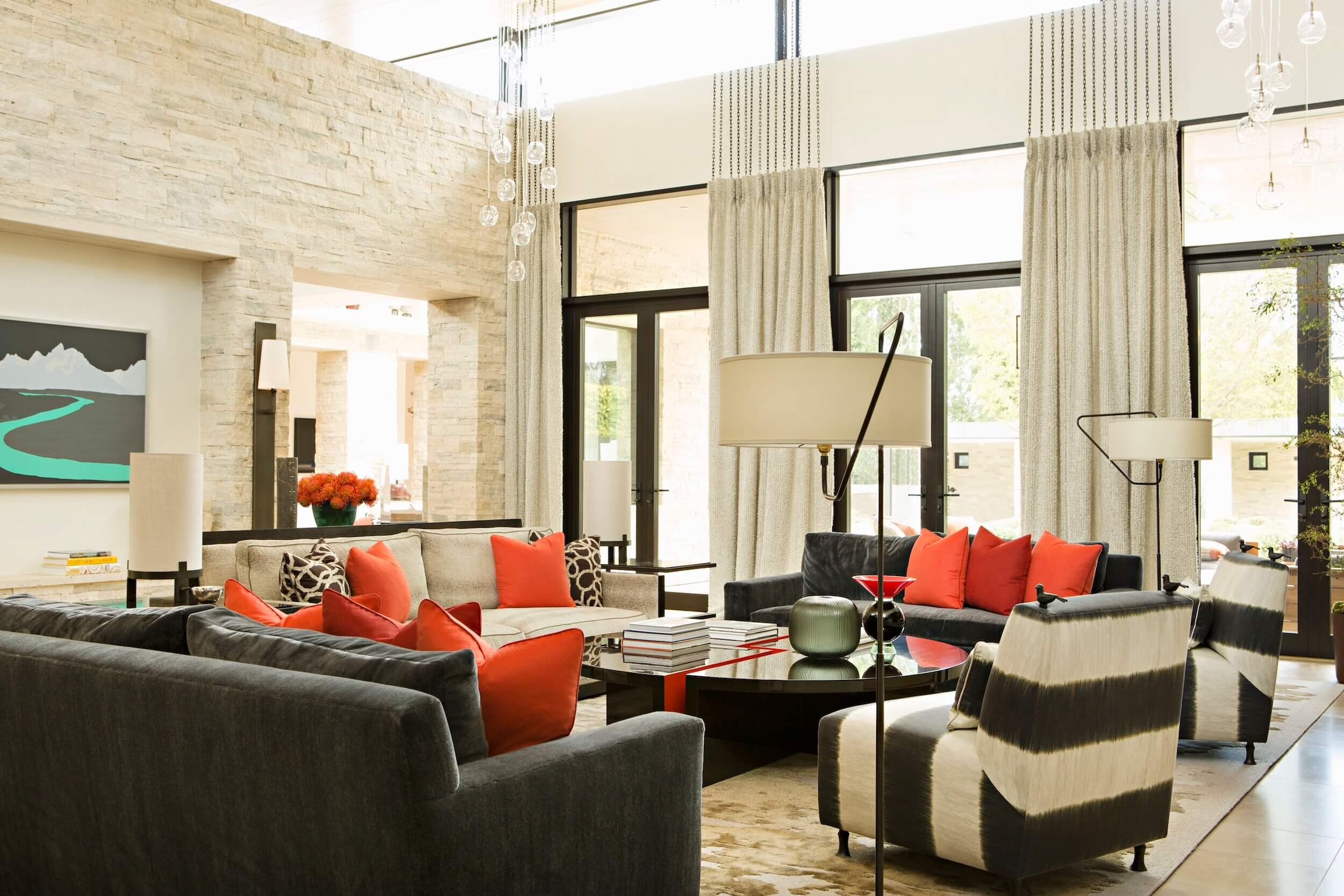 A Great Room with furnishing in a monochromatic palette accented by reds and a lacquered coffee table customized Dana John