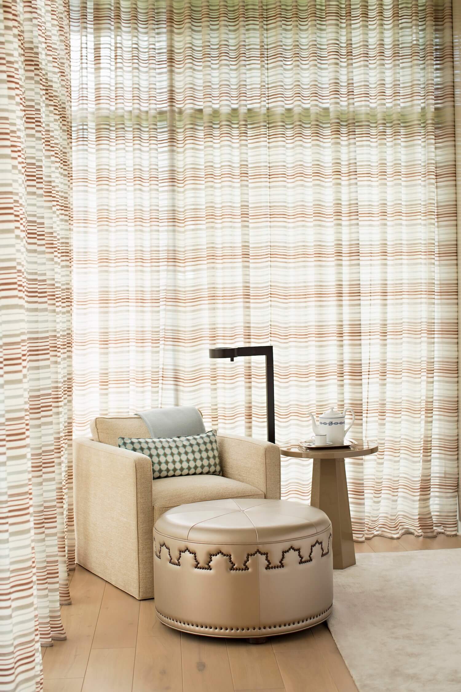 A leather upholster chair  in the corner surrounded by custom sheer drapery