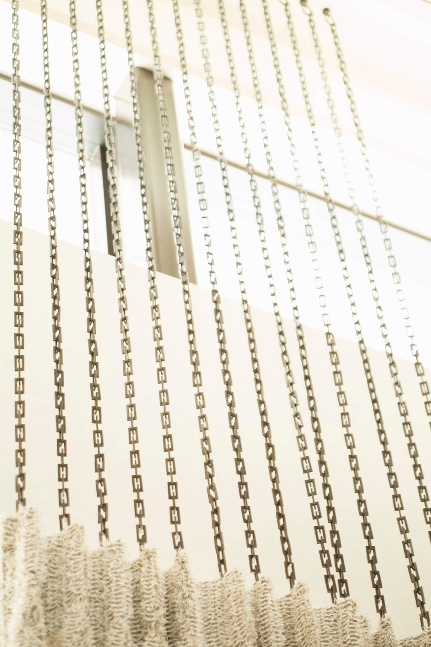 custom bespoke chains suspended from the ceiling are holding custom drapery made of Sahco Textiles
