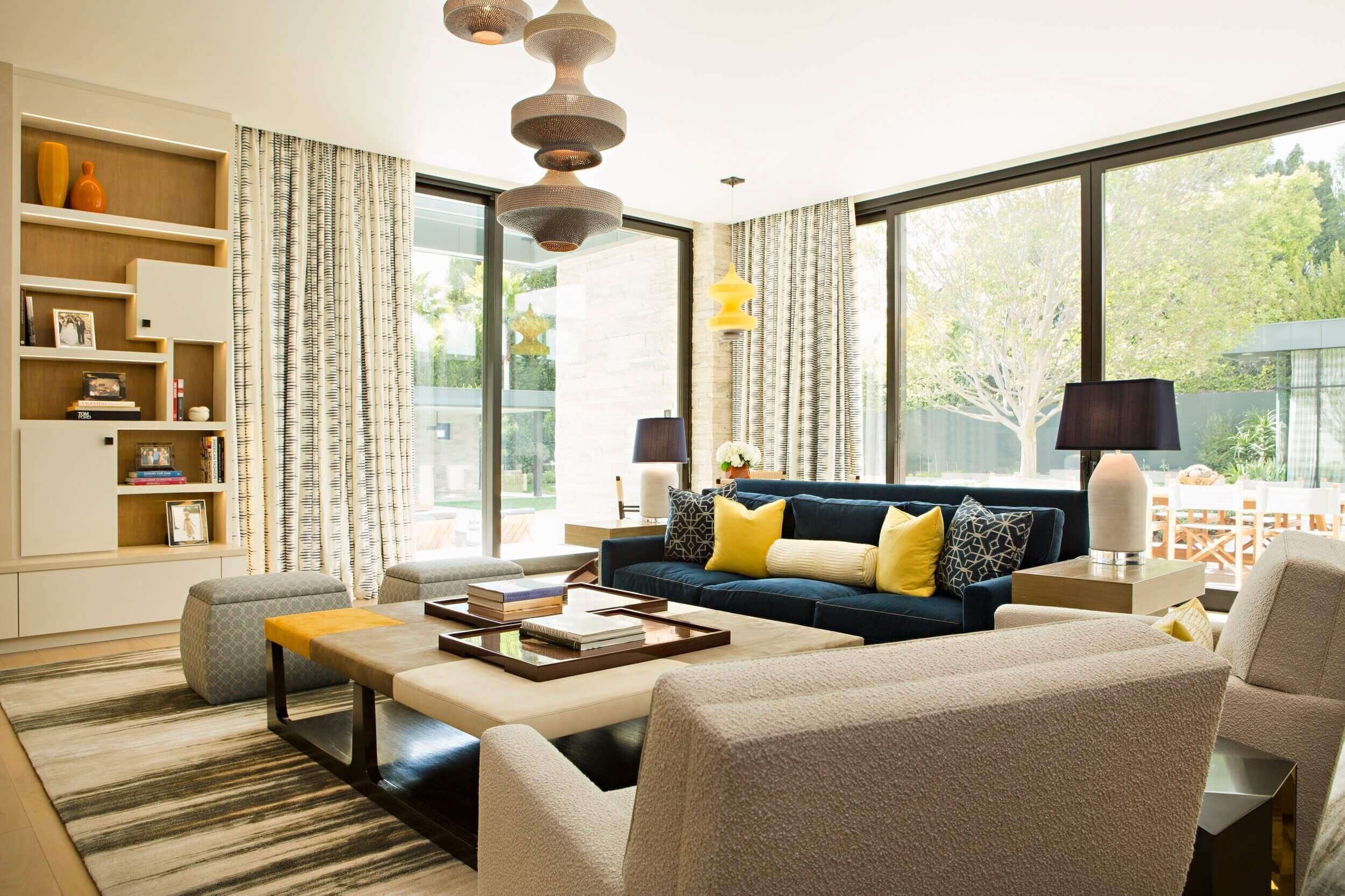 A large Family Room with Logo Piana blue corduroy sofas with accented yellows and Ceiling to Floor windows covered by custom drapery 