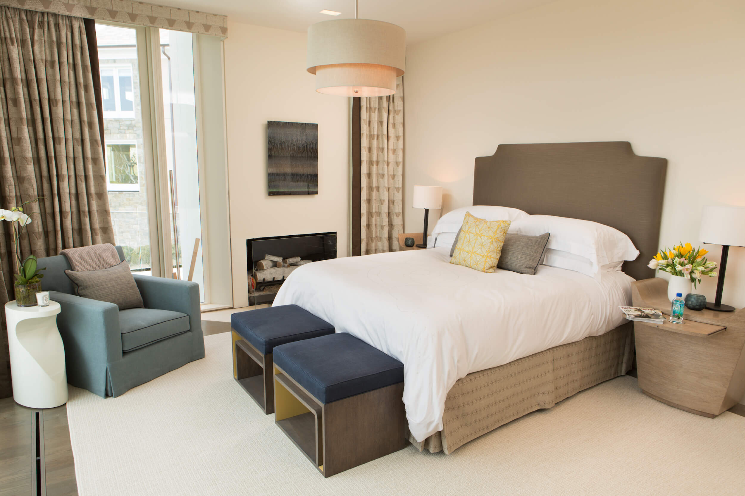 A Bedroom with an upholstered bed,  a contemporary chair in the corner and custom drapery 