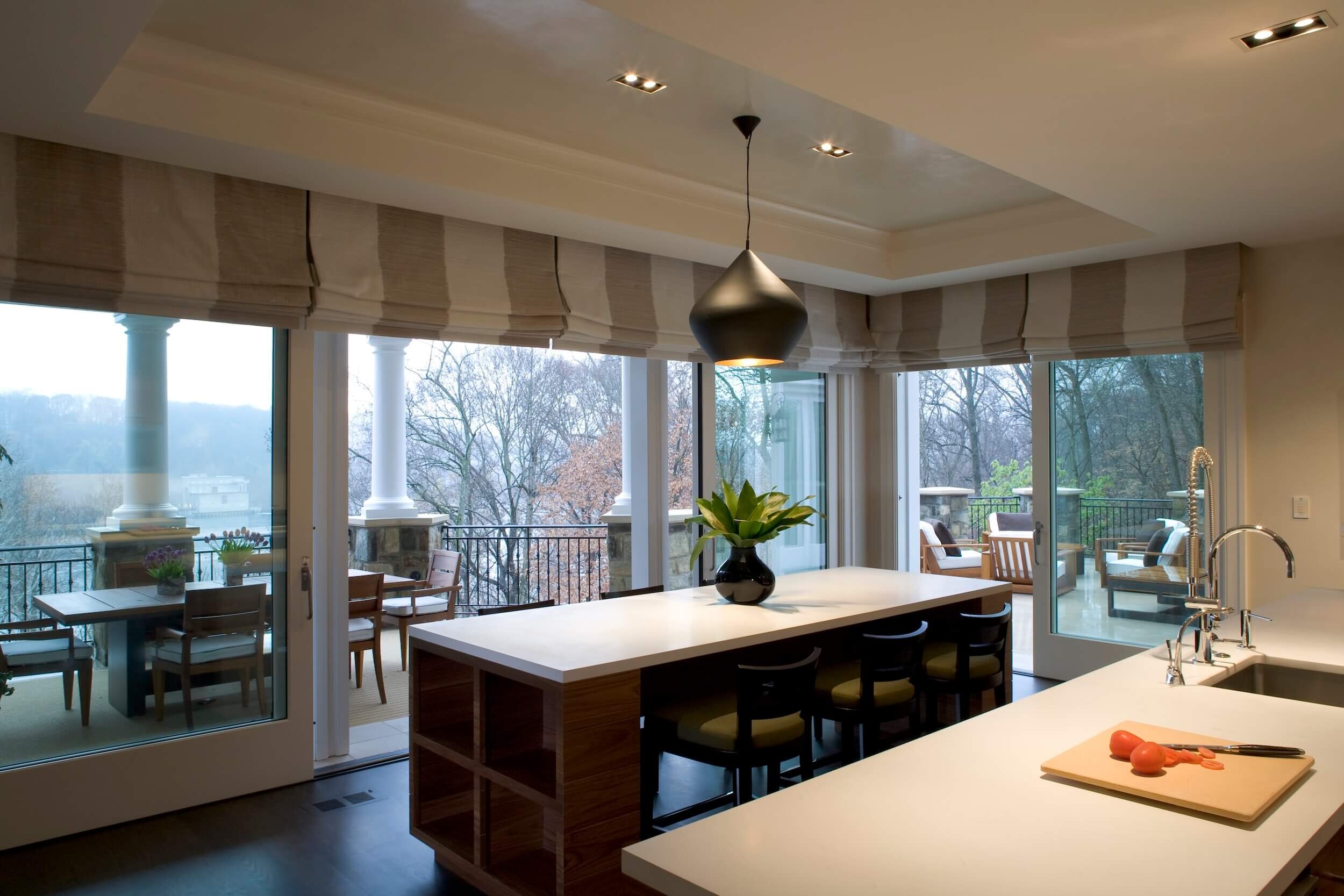 A Modern kitchen with an island surrounded by large sliding doors and custom roman shades