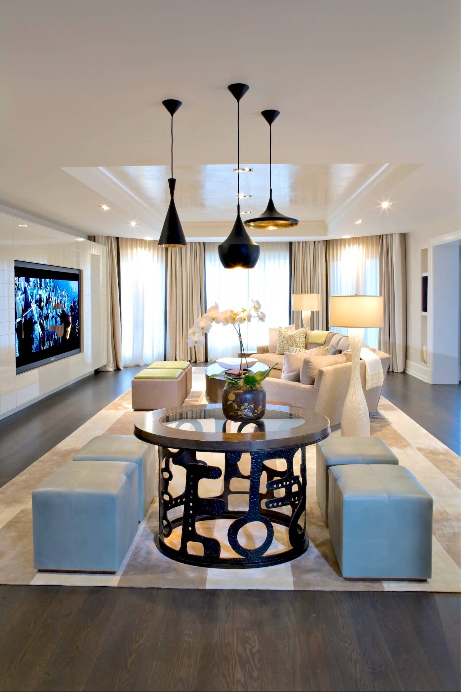 Family room with contemporary furniture in the center of the room with a entertainment system to the left and drapery with sheers