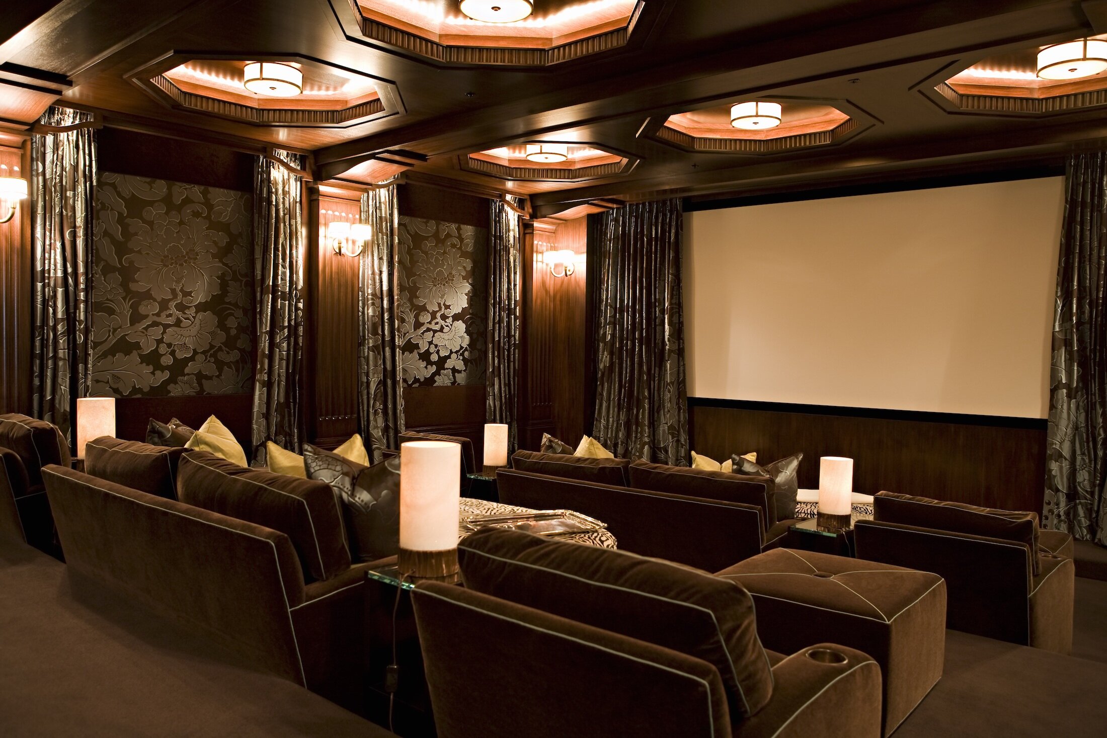Theater Room with upholstered seating, upholstery walls, custom drapery and a large movie screen