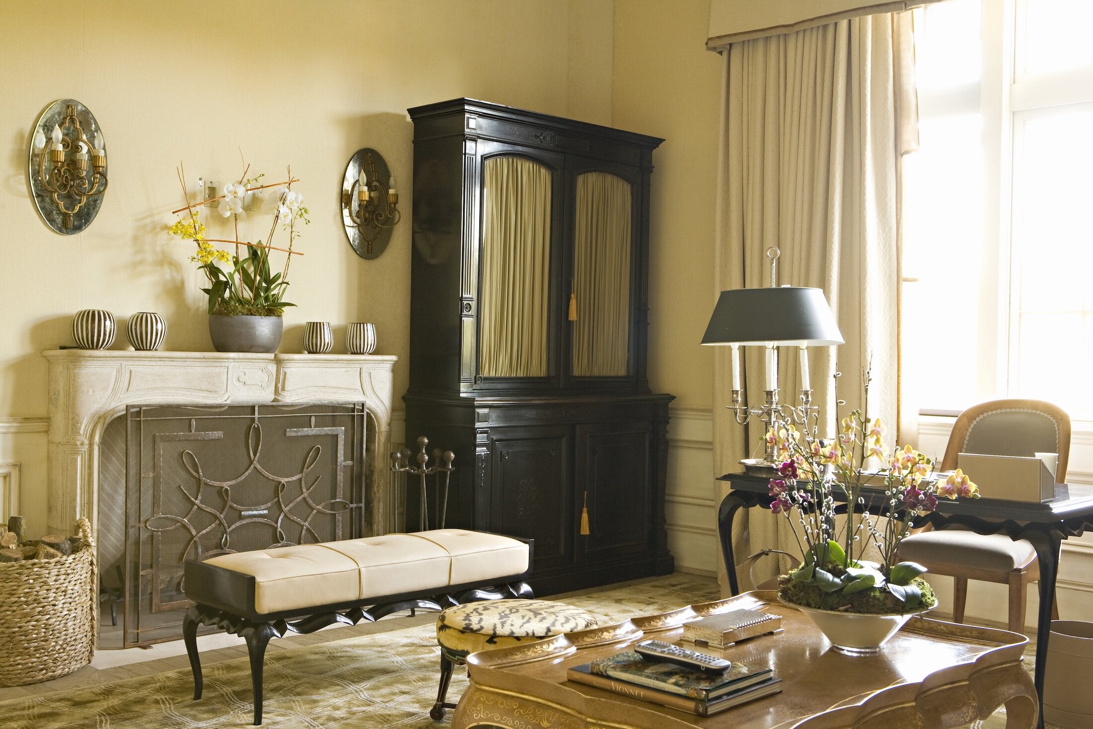 Master Sitting Room facing a fireplace with antique coffee table, sitting bench and custom drapery