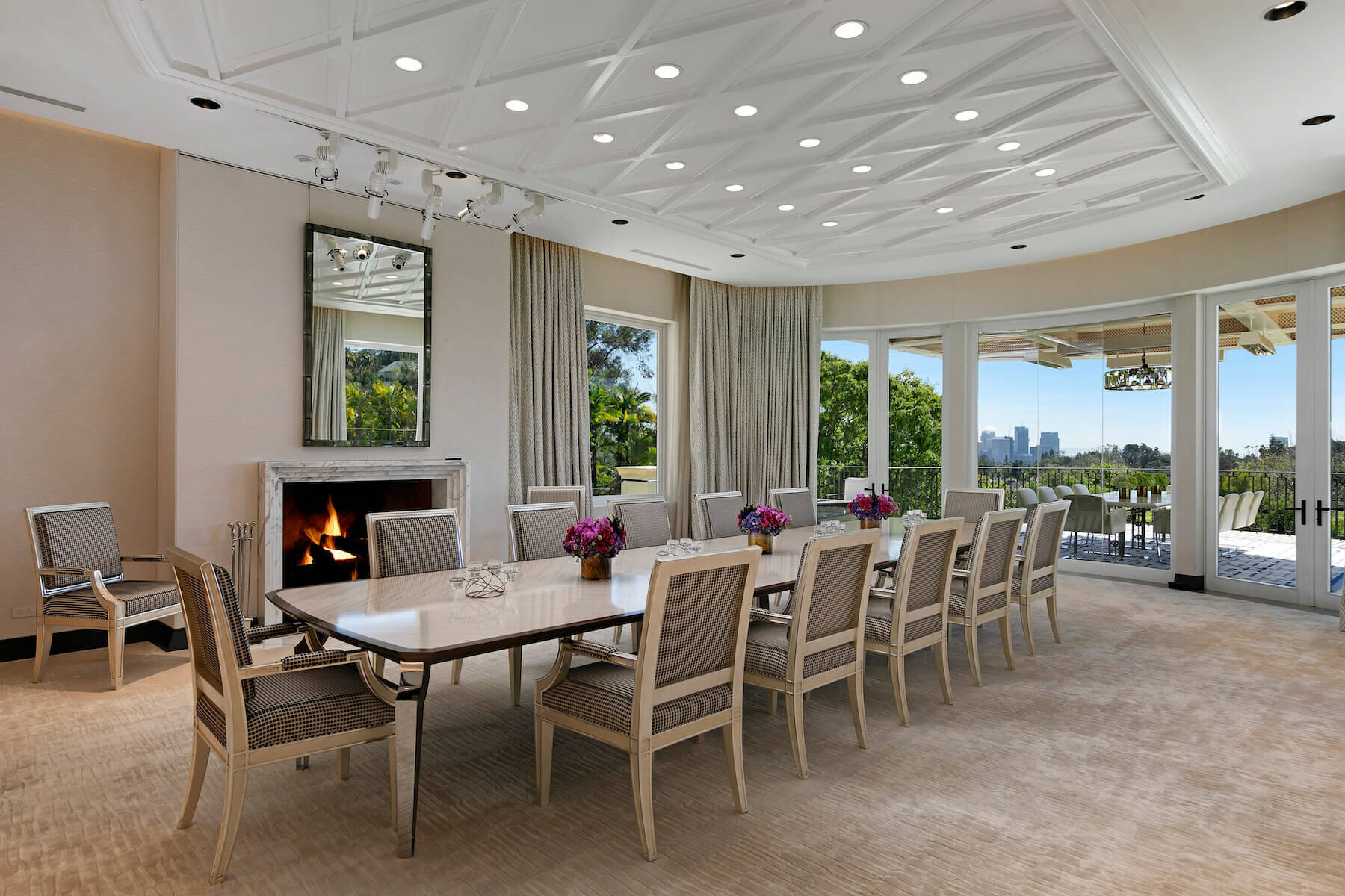 A grand Dining Room with large ceiling-to-floor windows, grand dining table with upholstered chairs and wall upholstery