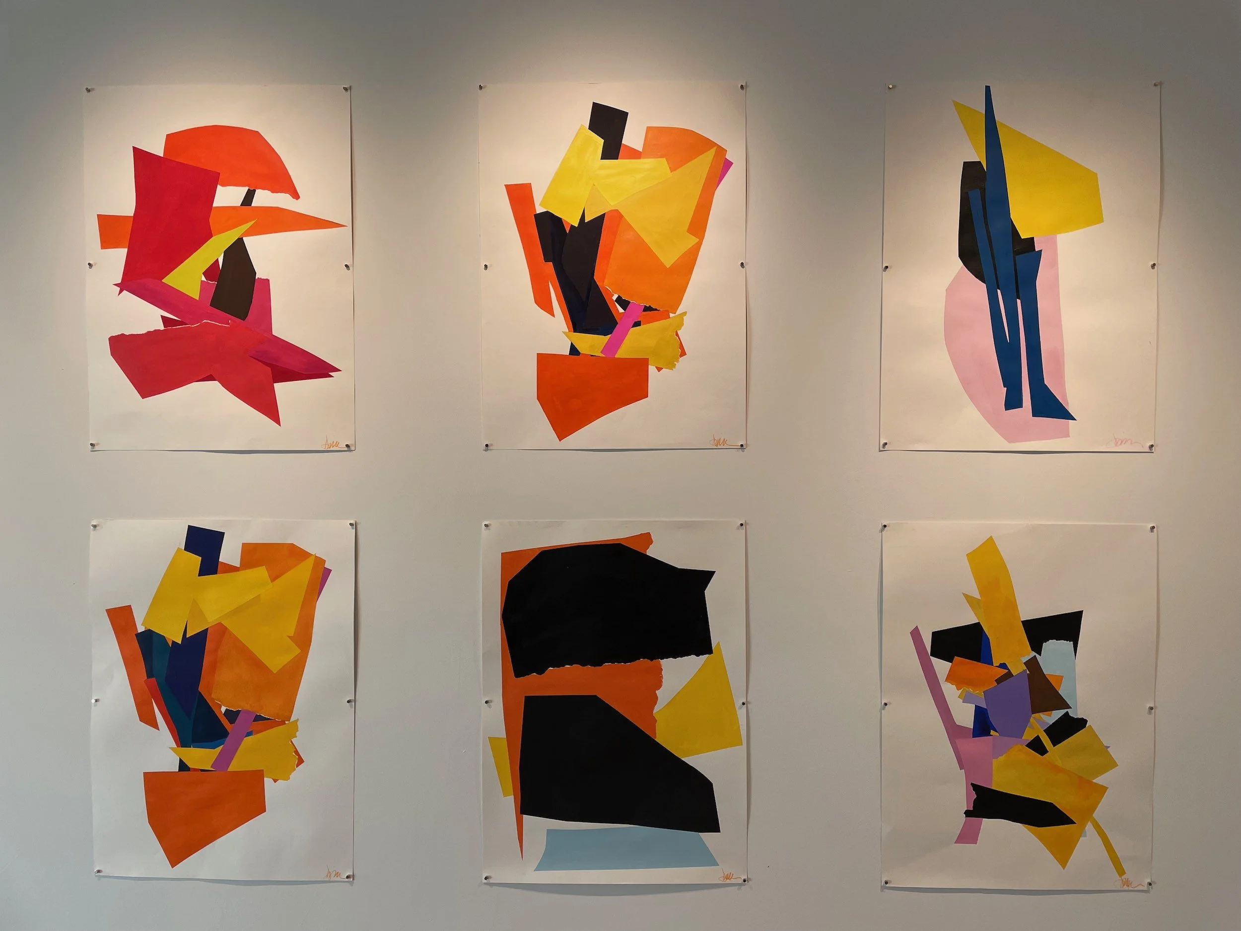 Six abstract colorful paintings with shapes and bold colors displayed on a white wall.