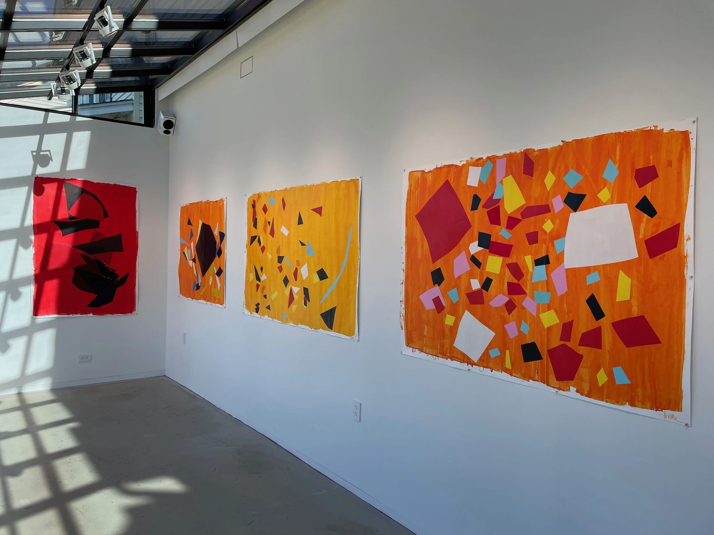 Gallery wall with four abstract paintings featuring geometric shapes and vibrant colors, set in a modern art museum space with natural light.