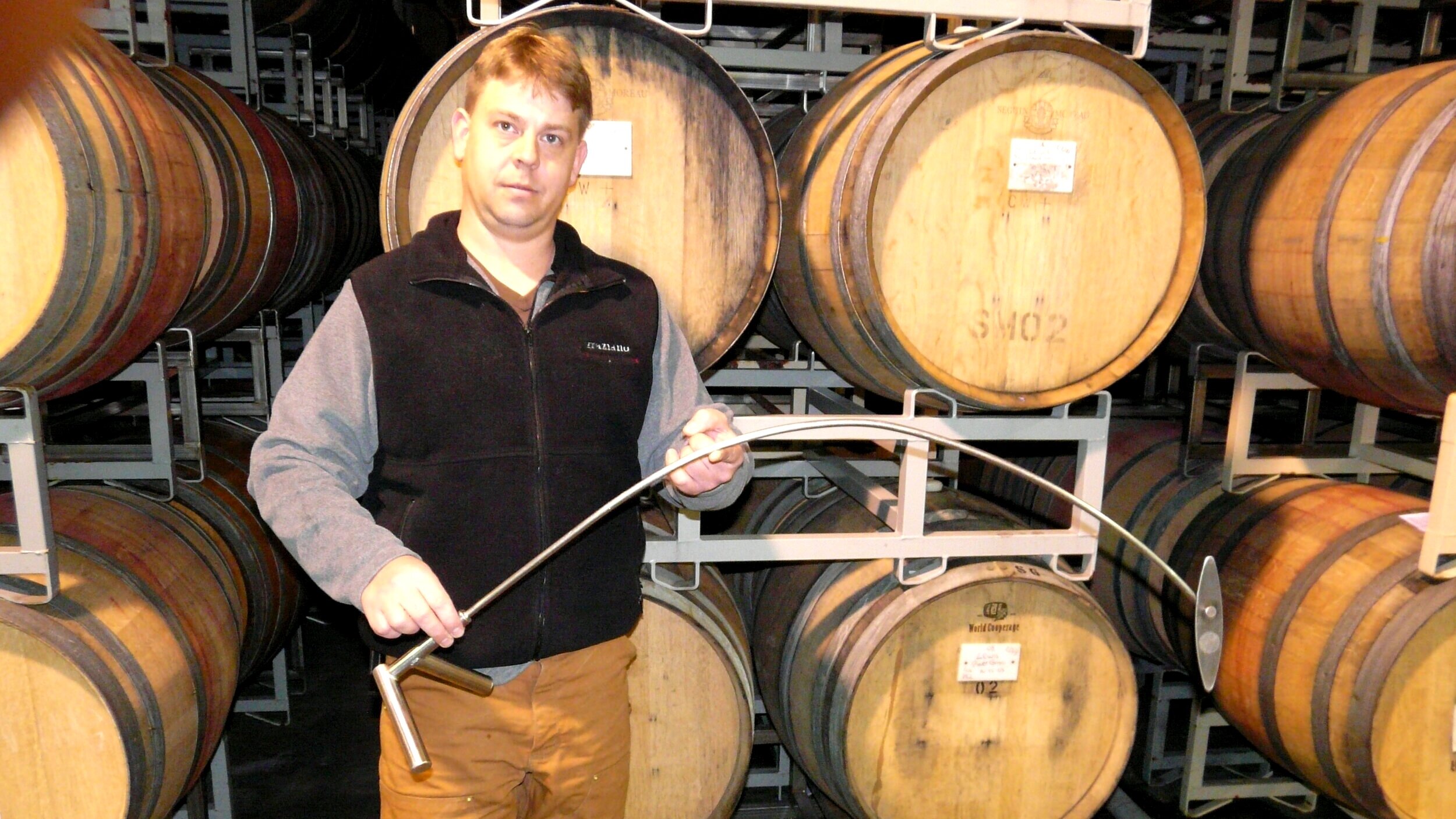 Cheson Boatwright holding a stir stick in front of barrels