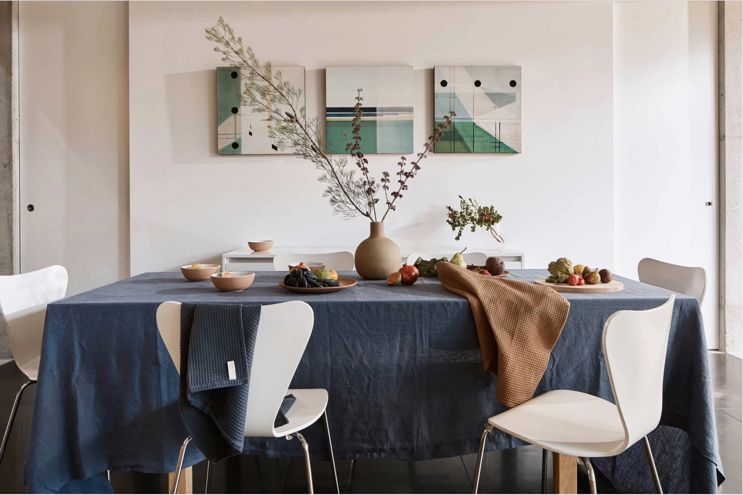 The dining table is set with tablecloth in French blue, organic cotton waffle teatowels in navy and toffee with a selection of ceramics by Lagos Del Mundo