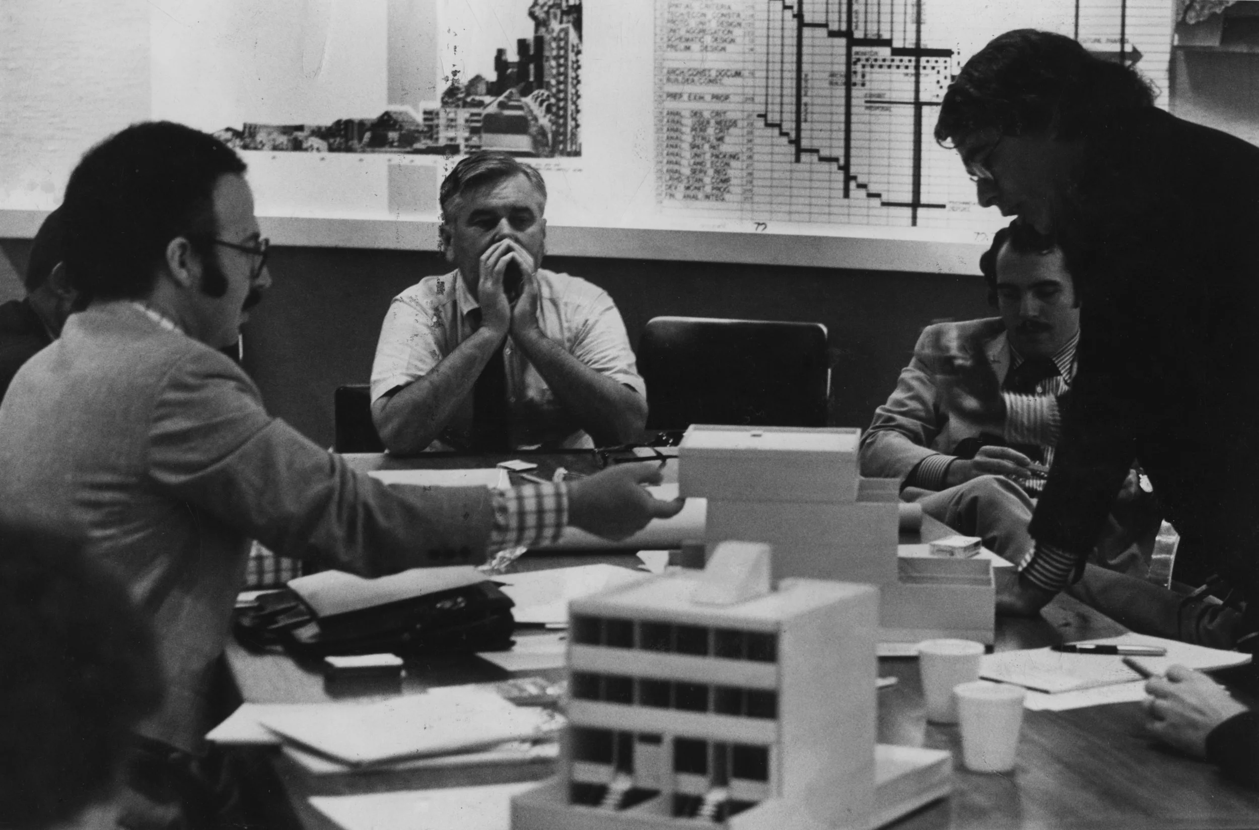 Figure 2. Marcus Garvey Park Village planning meeting, 1972. Ed Logue (center) is discussing the ideal housing prototype with chief UDC architect Ted Liebman (left) and architects Tony Pangaro (next to Logue) and Peter Eisenman (farther right). Courtesy of Robert Perron Photography.