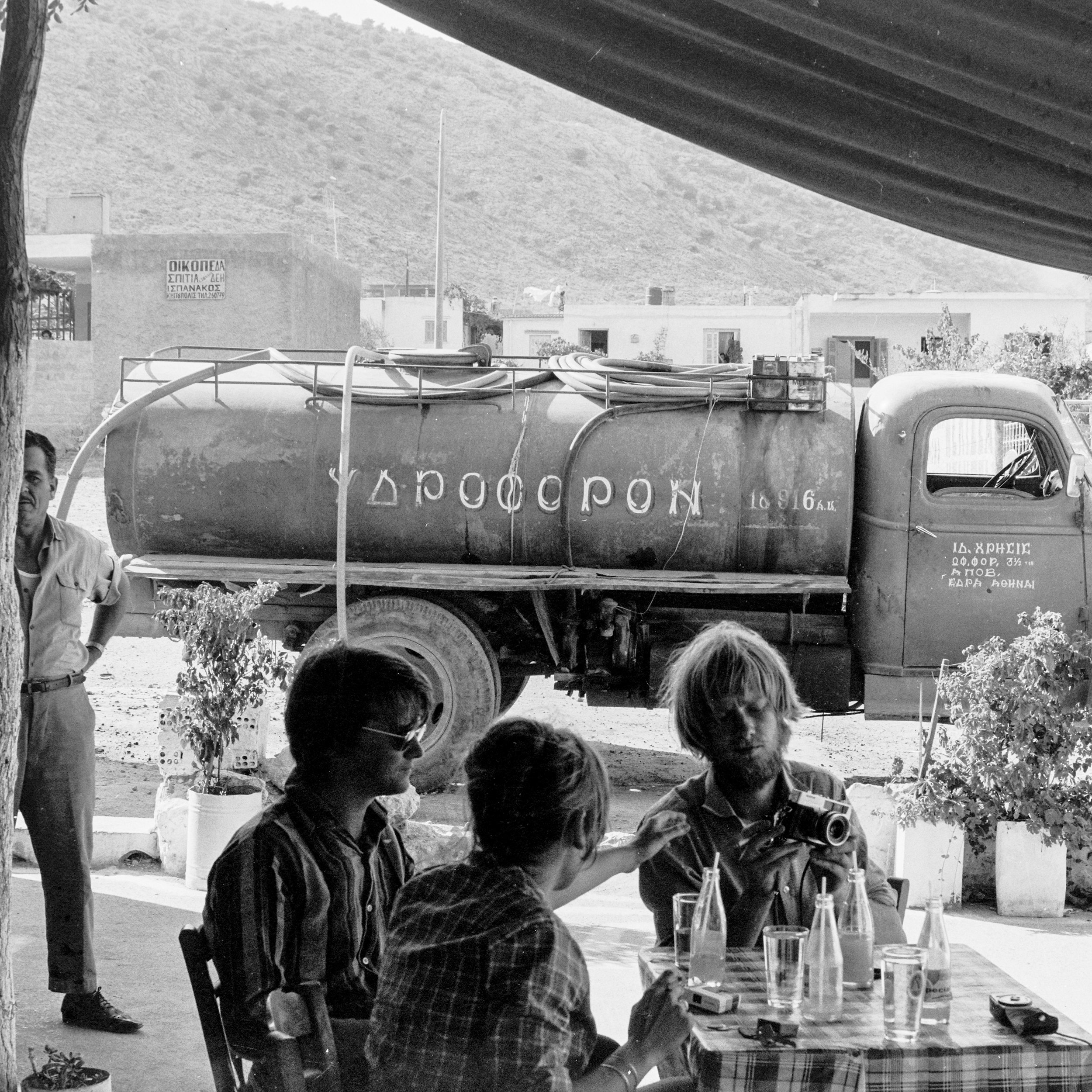  Figure 10. AA students at a local restaurant at  Kipoupolis , shot during the AA summer studio in 1969. Notice the water wagon behind them which provided drinking and washing water to dwellers. Reproduced with permission of Aristedes and Maria Roman