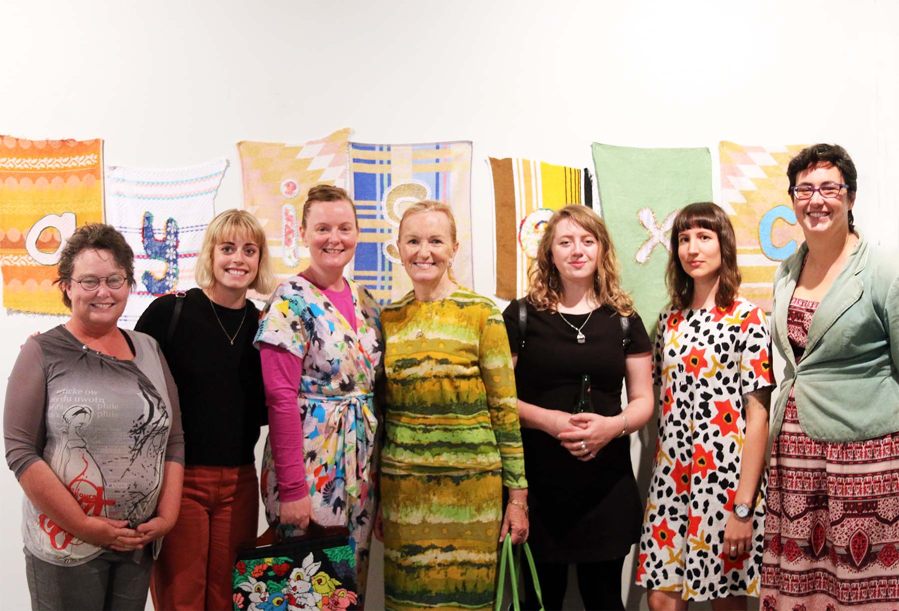   Left to Right : Amelia Rowe, Kathryn Camm, Mae Finlayson, Louise Parsons, Emma  Magnusson-Reid, Holly Leonardson, Karen Hall, in front of work by Mae  Finlayson.  Photography by Jo Pitchford  