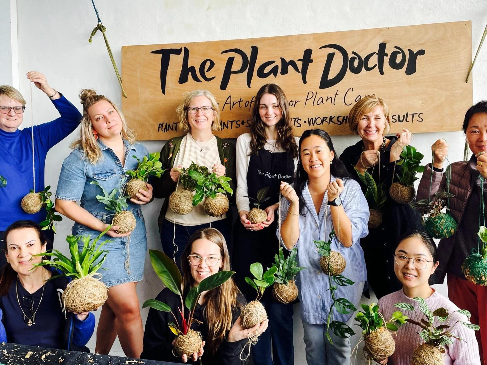happy people holding beautiful kokedama made during a team building activity
