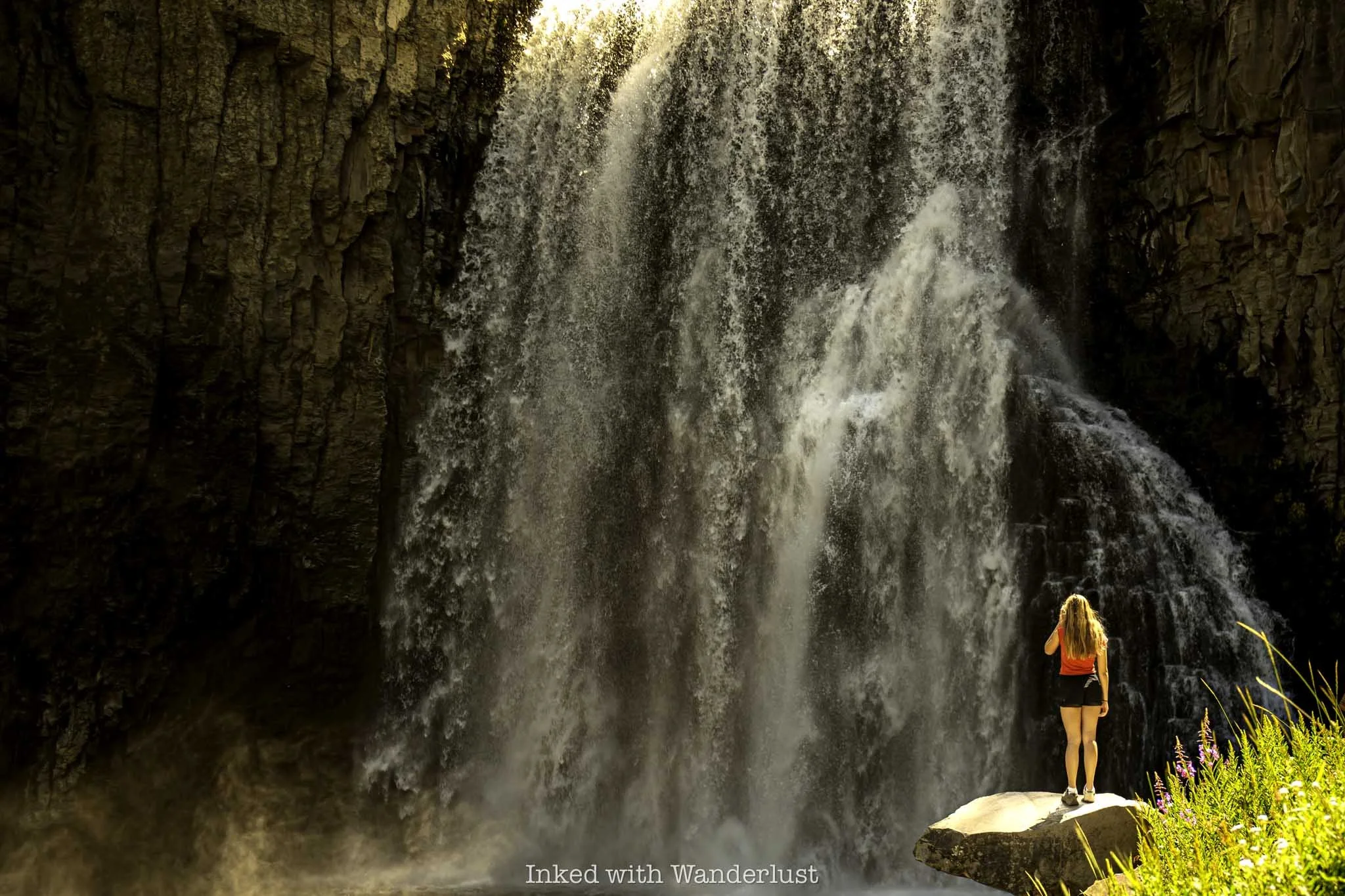 A woman posing in front of Rainbow Falls in California.