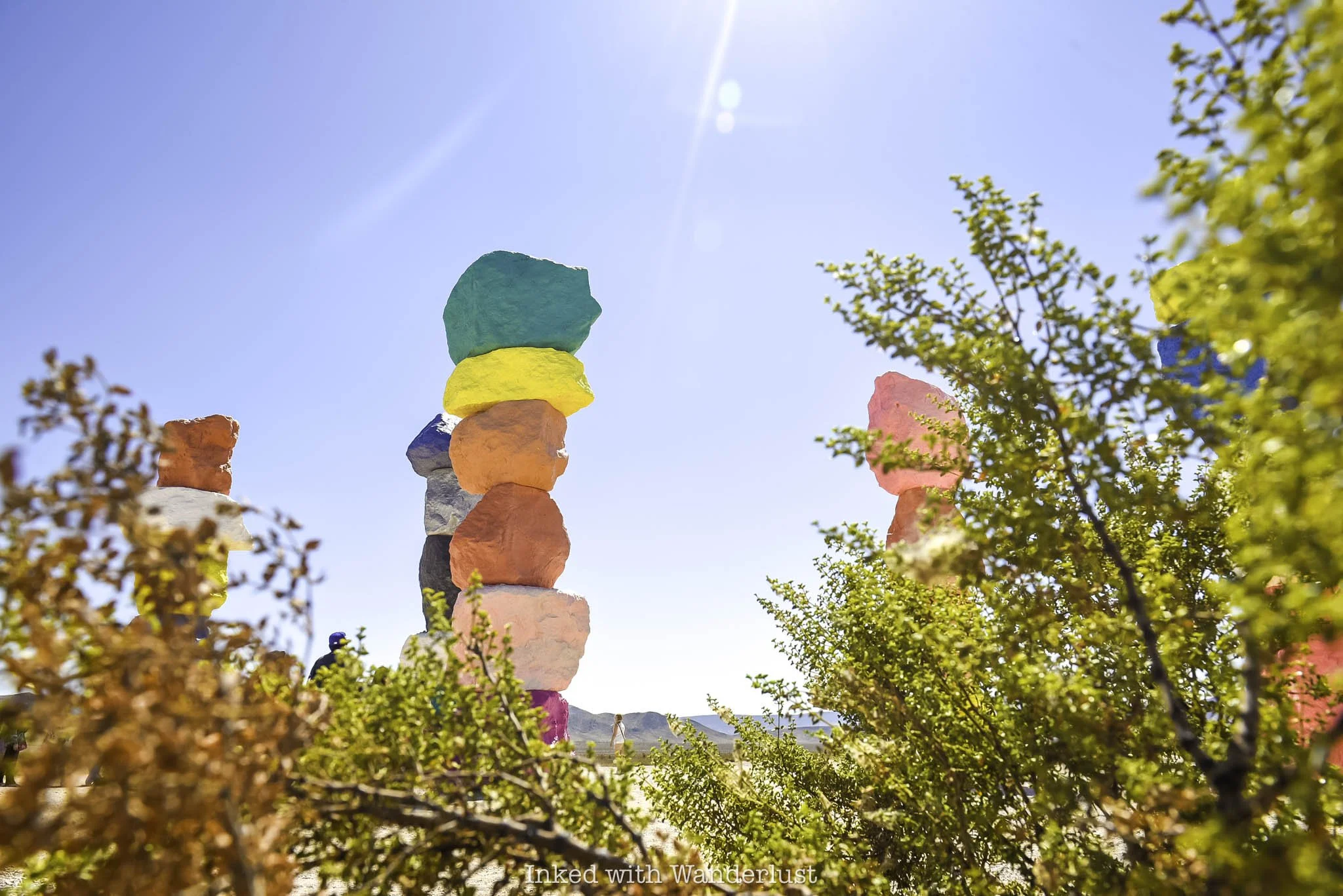 The Seven Magic Mountains artwork installation as viewed through bushes.