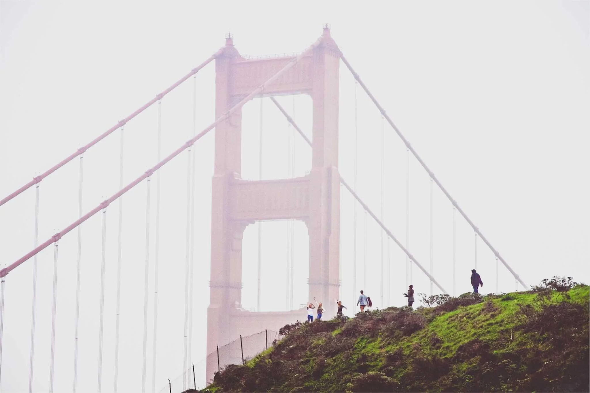 People posing for pictures in front of the Golden Gate Bridge.