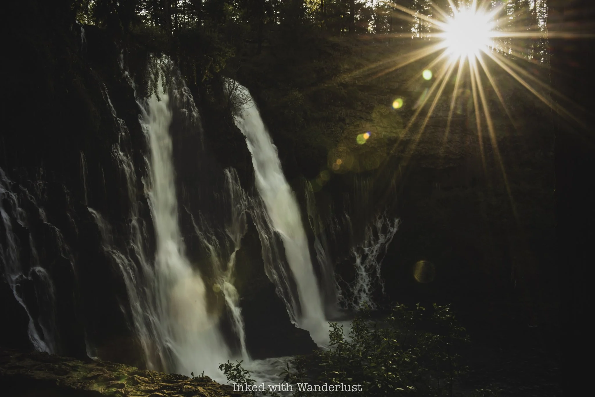 Burney Falls with a sun beam beaming through the trees.