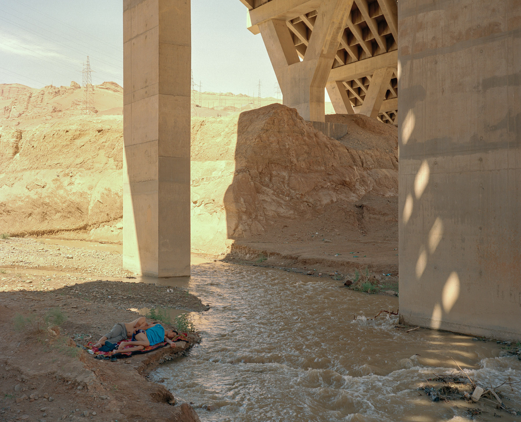  June 2016. Xinjiang province, China. On the road back from Turpan, a mostly Uighur oasis town, to Urumqi, Xinjiang's capital, we stop for a rest and see these two young Uighur men taking a nap under a bridge while the summer heat is reaching its pea