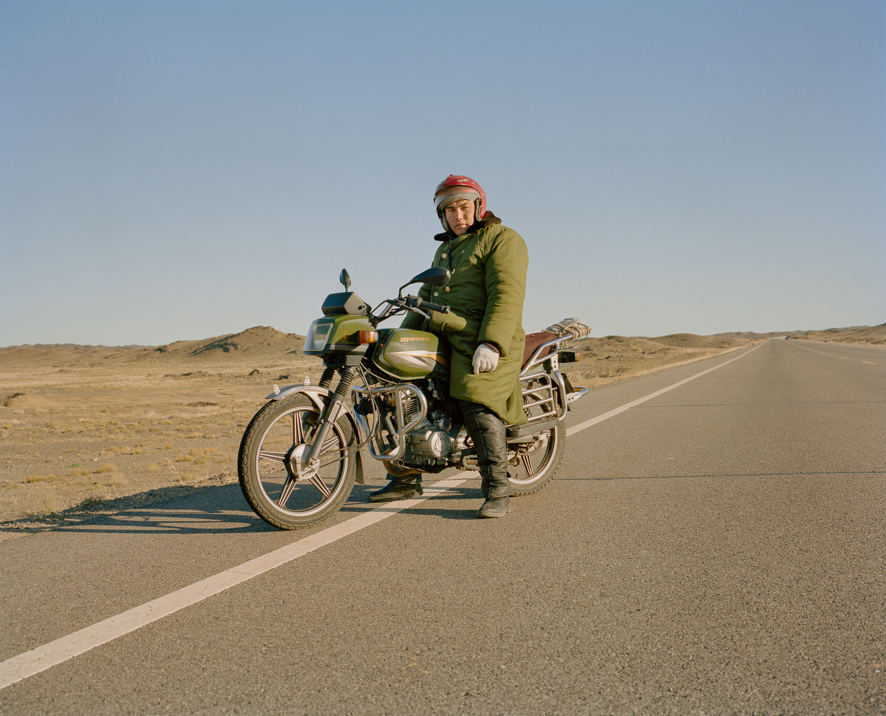  May 2016. Xinjiang province, China. Kazakh minority Chinese rider on a road in Northern Xinjiang province at the border with Khazakhstan.  