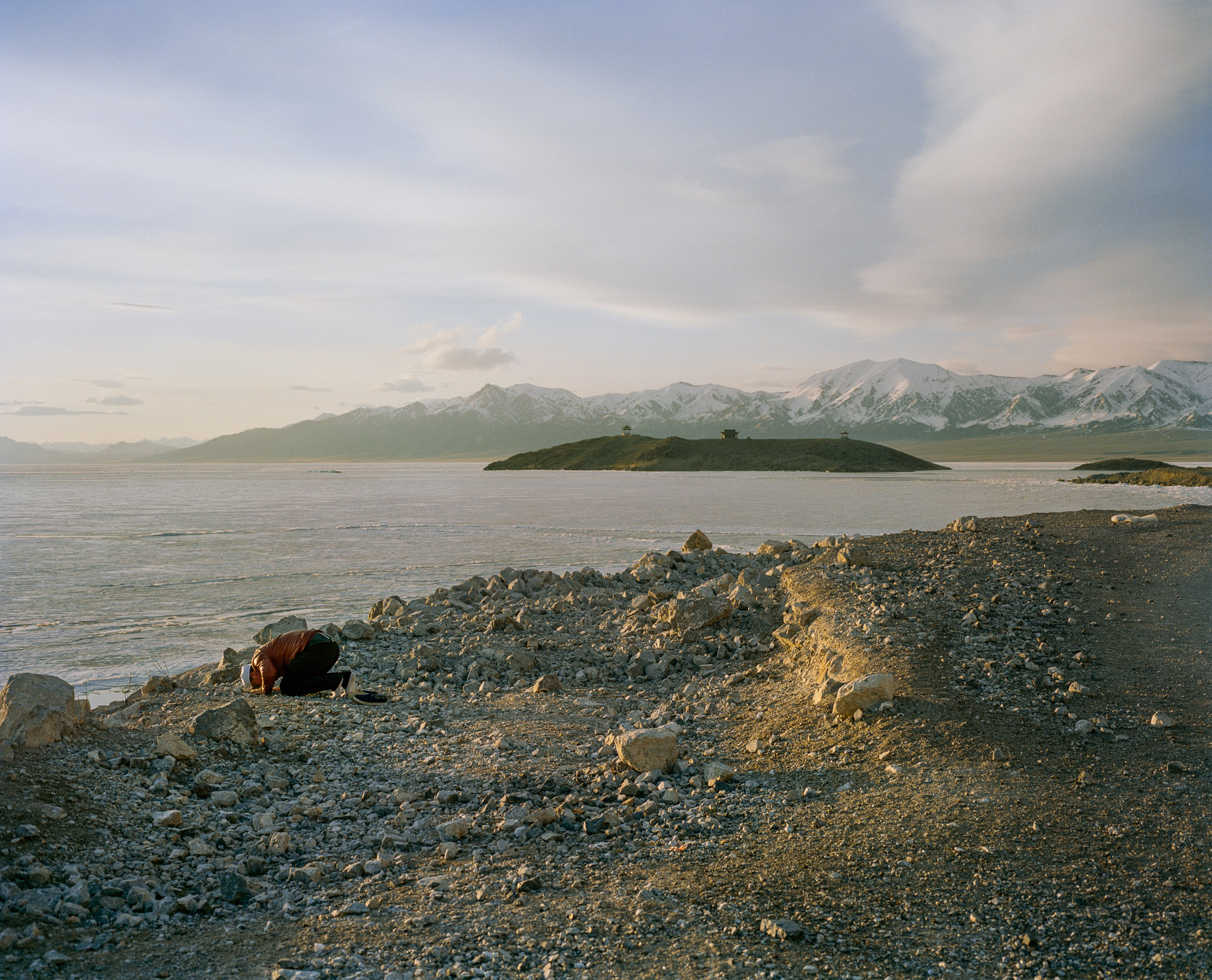  May 2017. Xinjiang province, China. Muslim man of the Hui minority praying at sunset on the shores of Saytam lake in the far-western Xinjiang province at the border with Kazakhstan.  