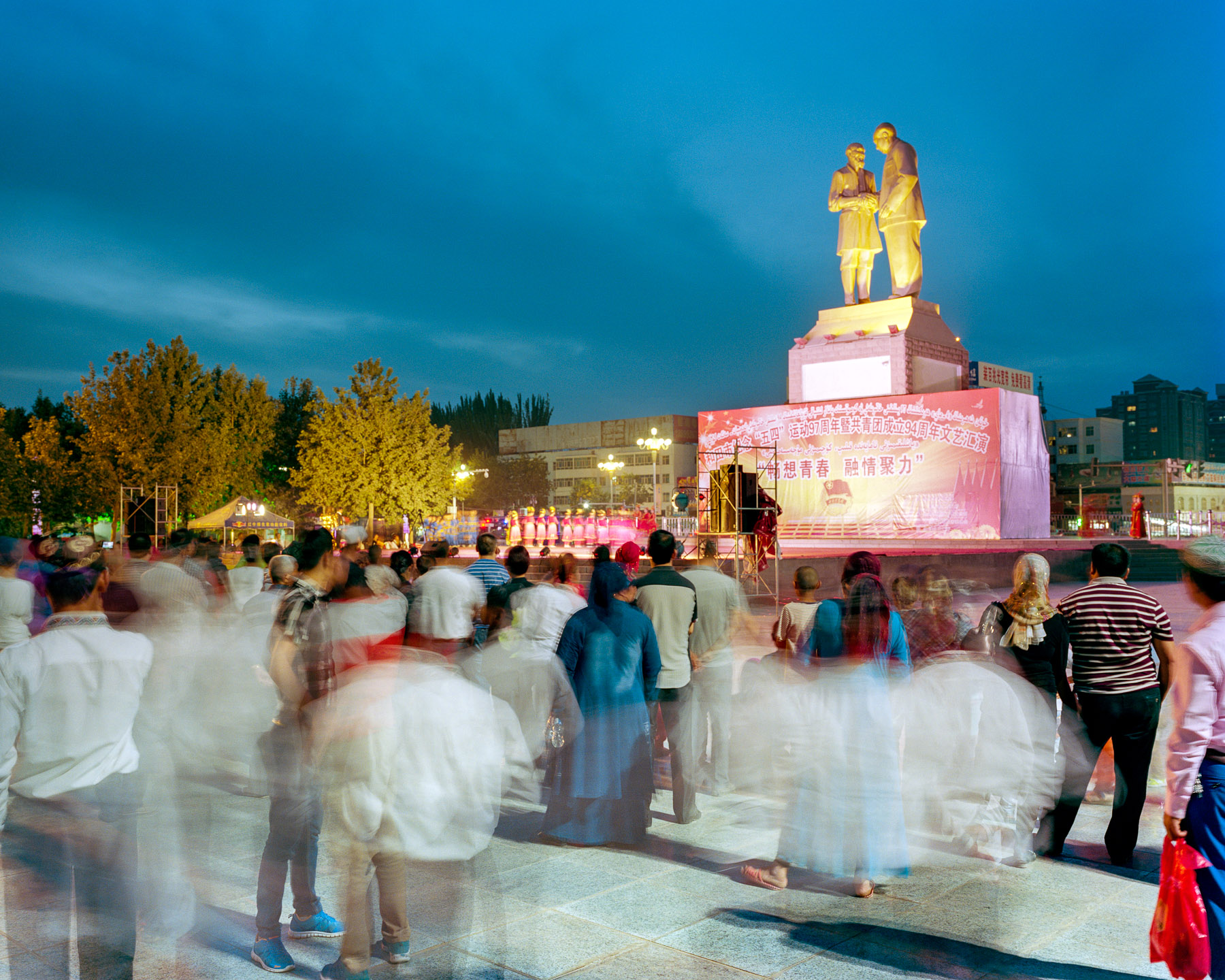  May 2016. Hotan, Xinjiang province, China. Tuanjie square which is Hotan's main square during a night event. In the center of the square stands the statue of Kurban Tulum's shaking hands with Mao Zedong.  