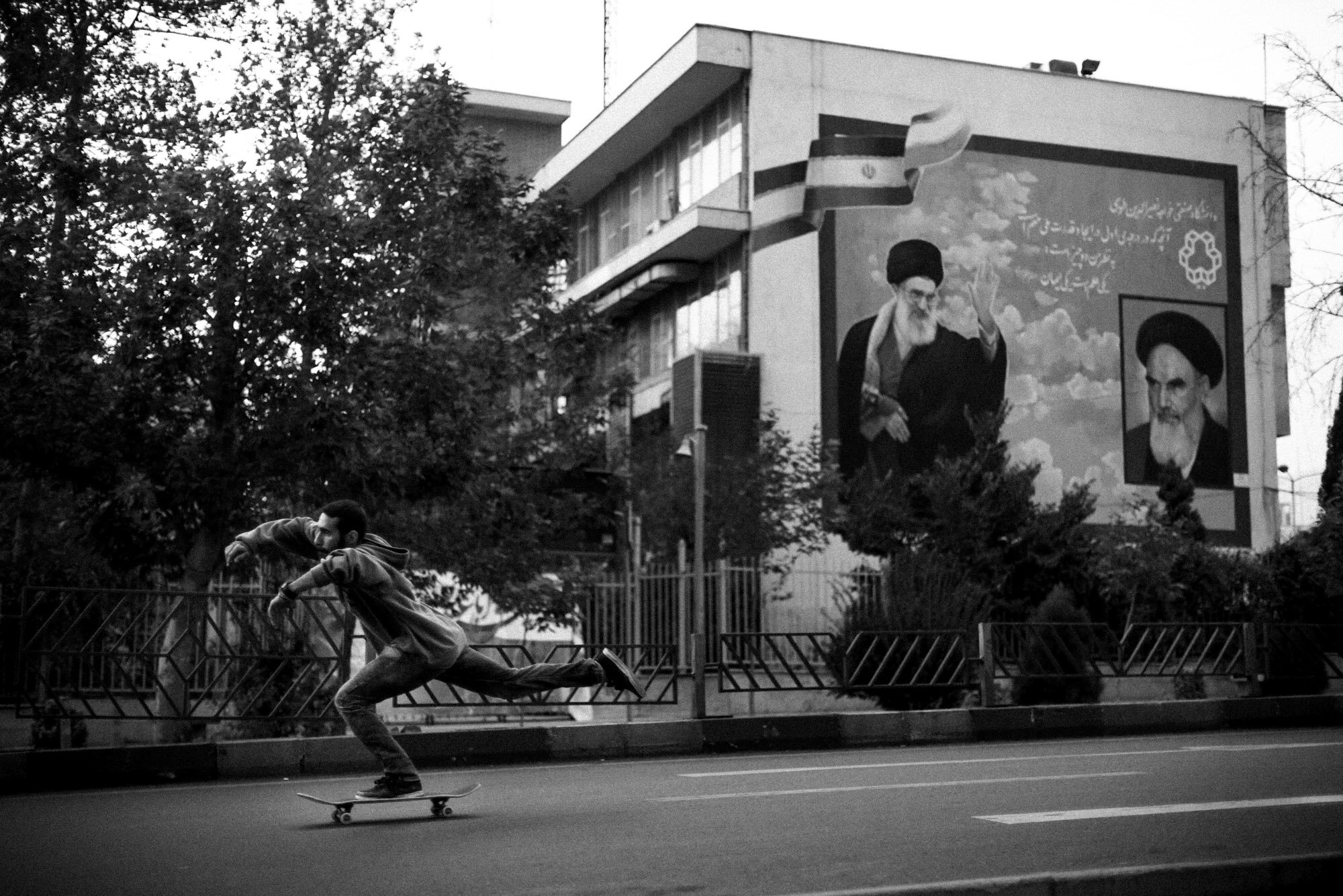  Erfan skateboards down Valiasr street in Tehran. He rides in front of the portraits of Khomeini and Khamenei, The Supreme Leaders of the Islamic Republic. Tehran, Iran, October 23, 2015. 