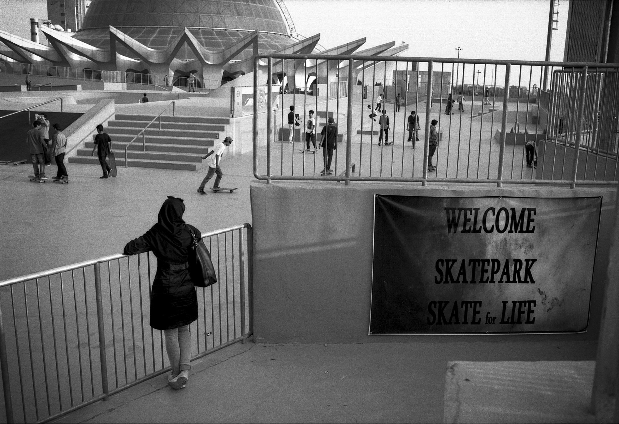  In Ab-o-Atash skatepark, a woman watches the boys practicing. Tehran, Iran, September 21, 2015. 