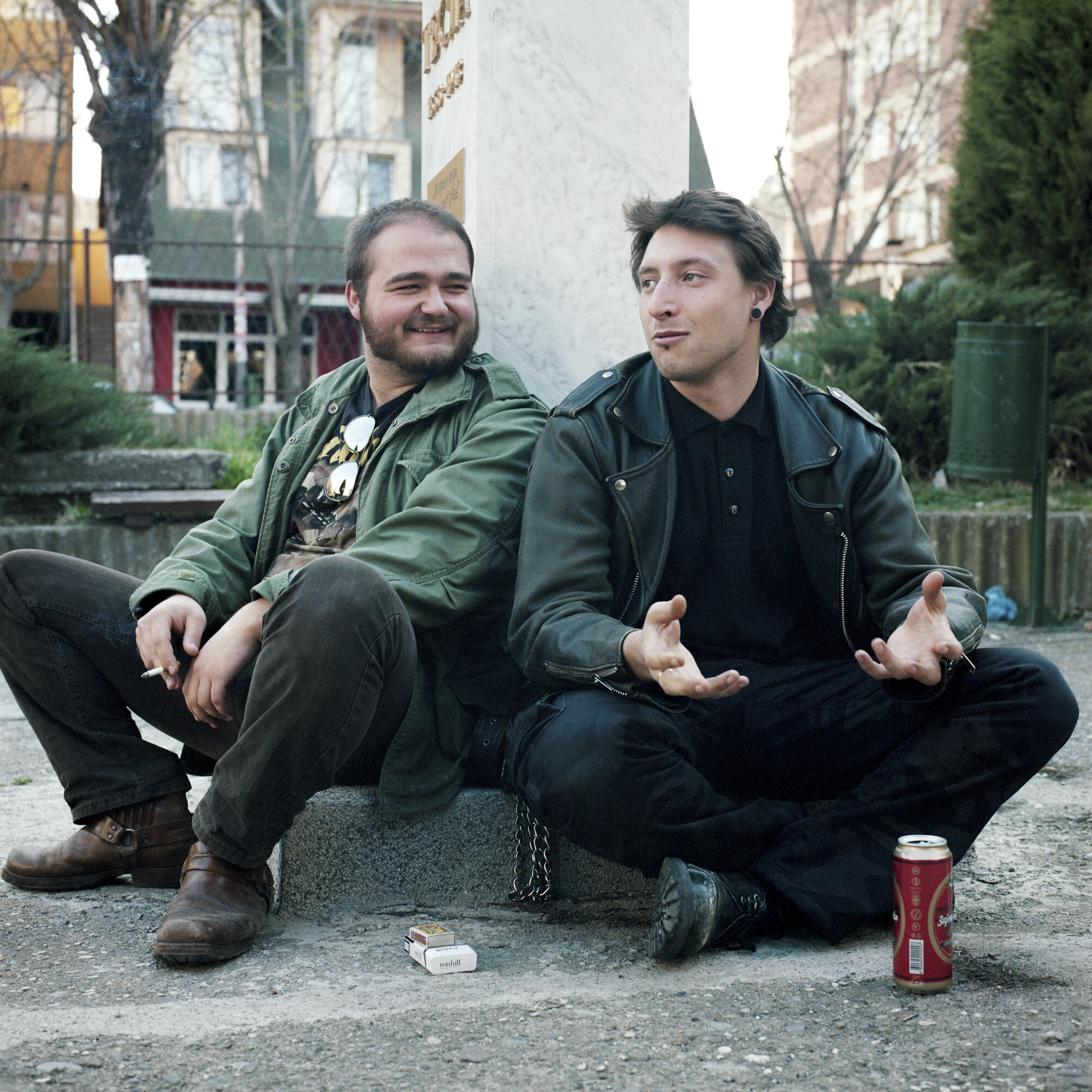  After rehearsals with their death metal band, Alem (on the right) and Boris (on the left),  two young rockers who live in the Serbian part of Mitrovica, drink beers and smoke cigarettes in a public park. Mitrovica, Kosovo, March 28, 2017. 