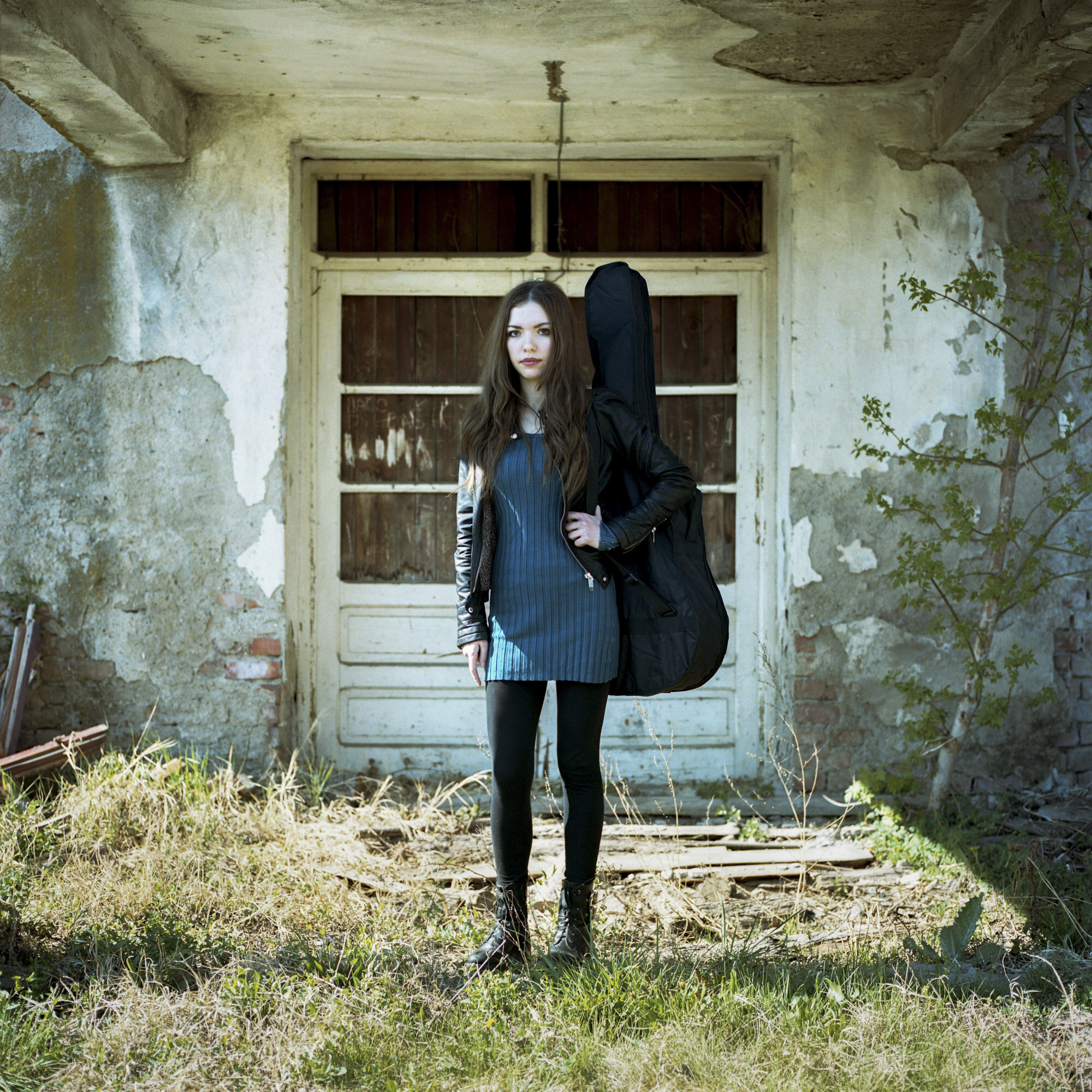  Jelena Zafirovic, 27 years old Serb, poses whit her guitar gig bag in front of an abandoned house located in the Serbian part of Mitrovica, Kosovo. Jelena is student at the Mitrovica Rock School and singer in the multi-ethnic band "Sublim 6". Mitrov