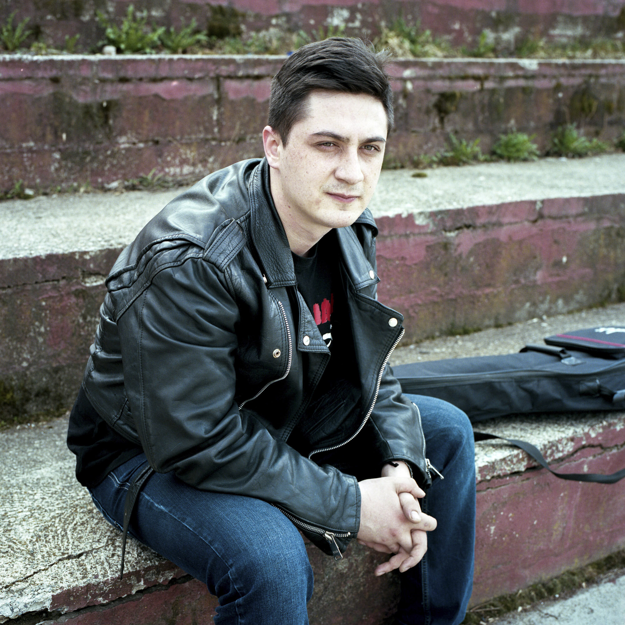 Nemanja Blagojevic, a 23 years old Serb, sits with his guitar in the stands of a basketball court in Zvecan, Kosovo. Nemanja is student at the Mitrovica Rock School and singer in the mixed band IFO. Zvecan, Kosovo, March 27, 2017.