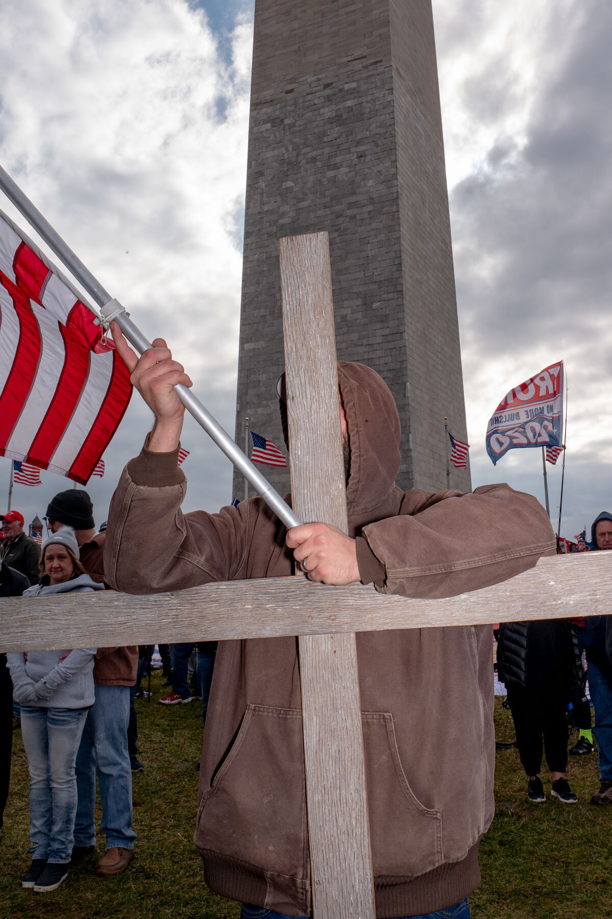  January 6th 2021 - A Trump supporter is holding a cross and an American flag in front of the Washington Monument during the last Trump rally in front of the White House that led to the Storming of the Capitol on January 6th. 