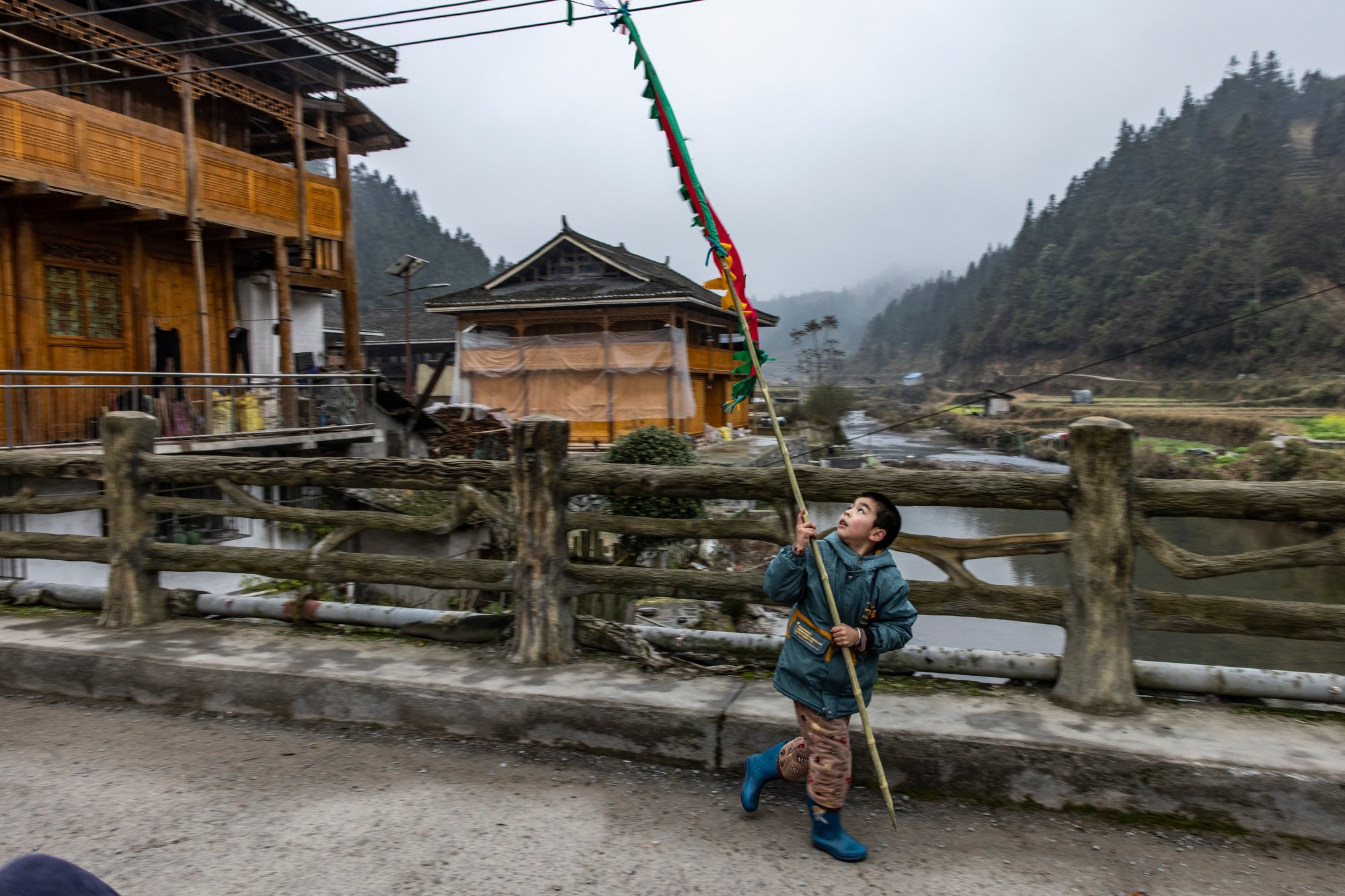  A boy with the village flag runs in front of the crowd that is accompanying the buffalo to the arena, where it will attend the first fight of the year. Zhengying village in Guizhou, China. 
