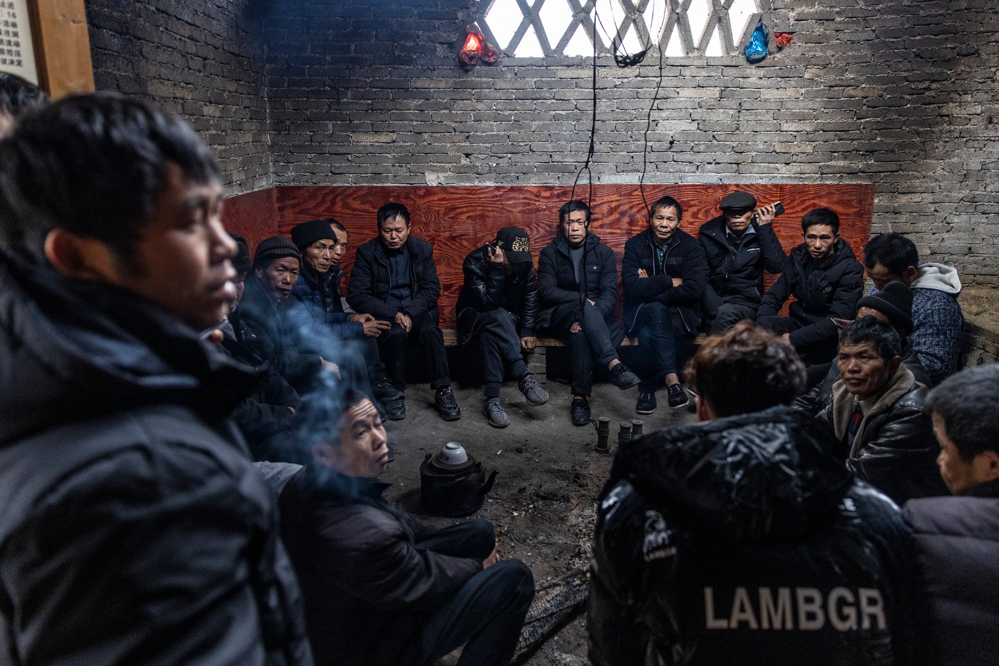  The village elders gather around a fire in the buffalo shack on the day the buffalo leaves to the fight. Zhengying village in Guizhou, China. 