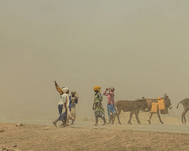 A la foto veiem un grup de dones que transporten aigua amb burros. El que podria semblar una tempesta de sorra no &eacute;s m&eacute;s que pols aixecada per els cotxes que passen a gran velocitat; dons aquests han d'anar per fora la carretera ja que 