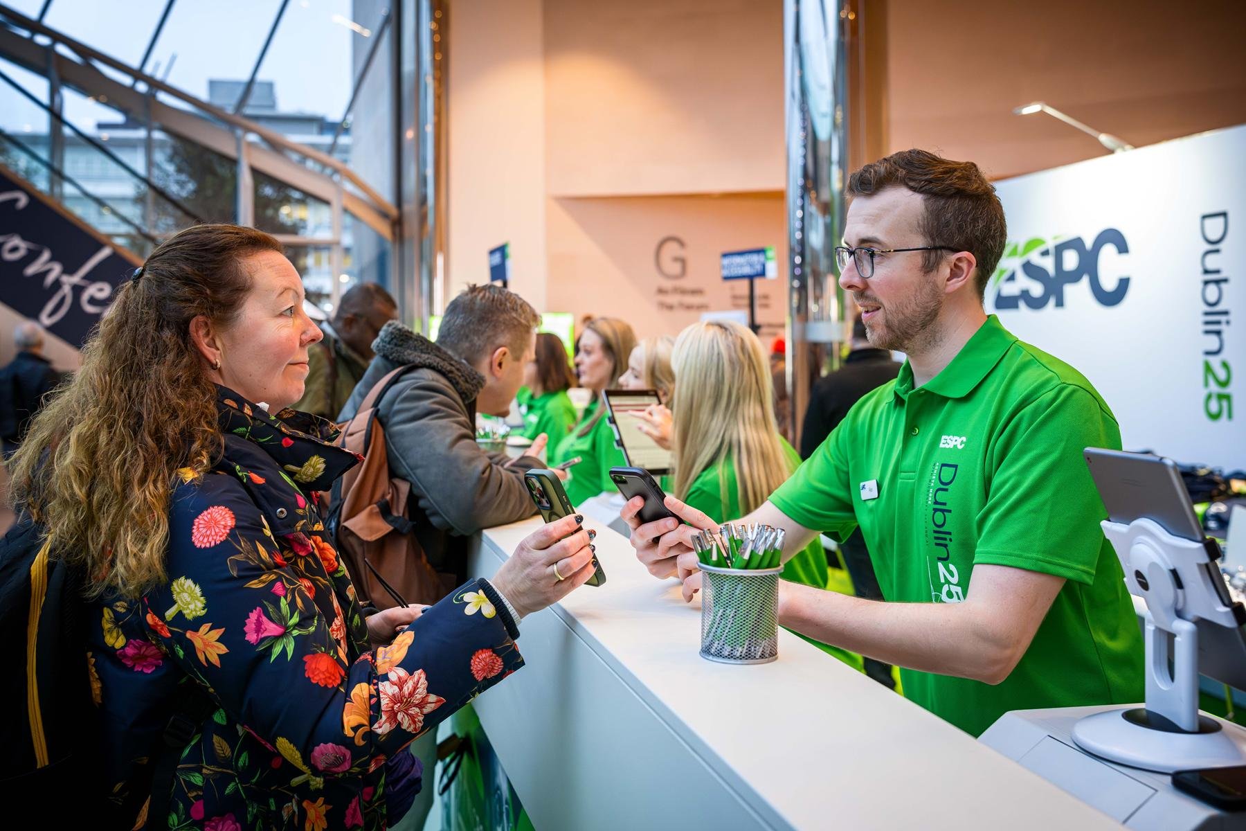 A member of registration staff uses a QR scanner supplied by Event Connections to scan an invite on a mobile device to print a badge