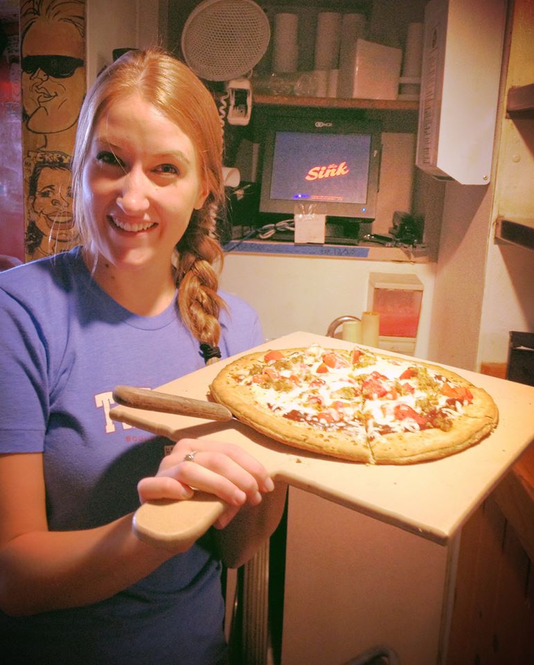 Waitress showing off a mouthwatering pizza in the expo line at The Sink