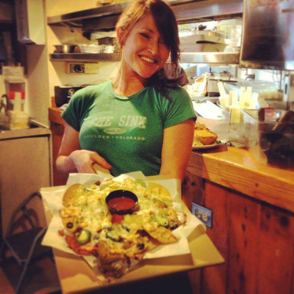 Waitress smiling and holding Sink Nachos before bringing them to a table