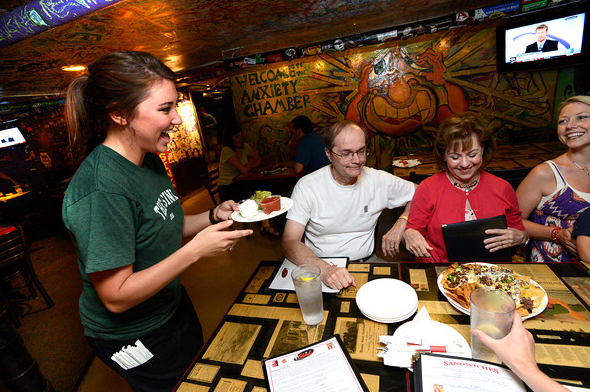 Waitress serving food to happy patrons in The Sink