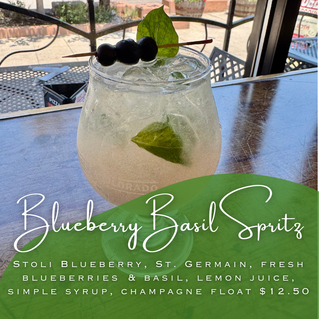 Sparkling drink with blue berrues and basil with window in background