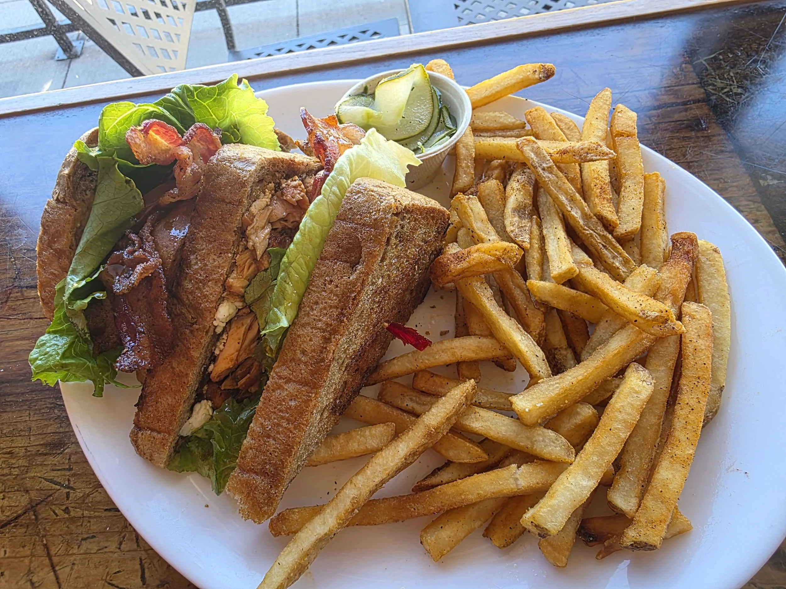 Salmon sandwich with fries on white plate