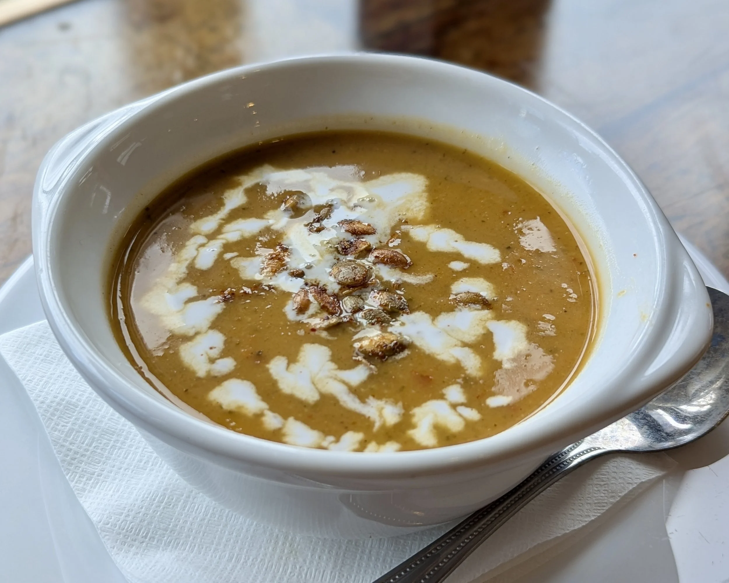 Bowl of curry soup with a coconut drizzles and pumpkin seeds