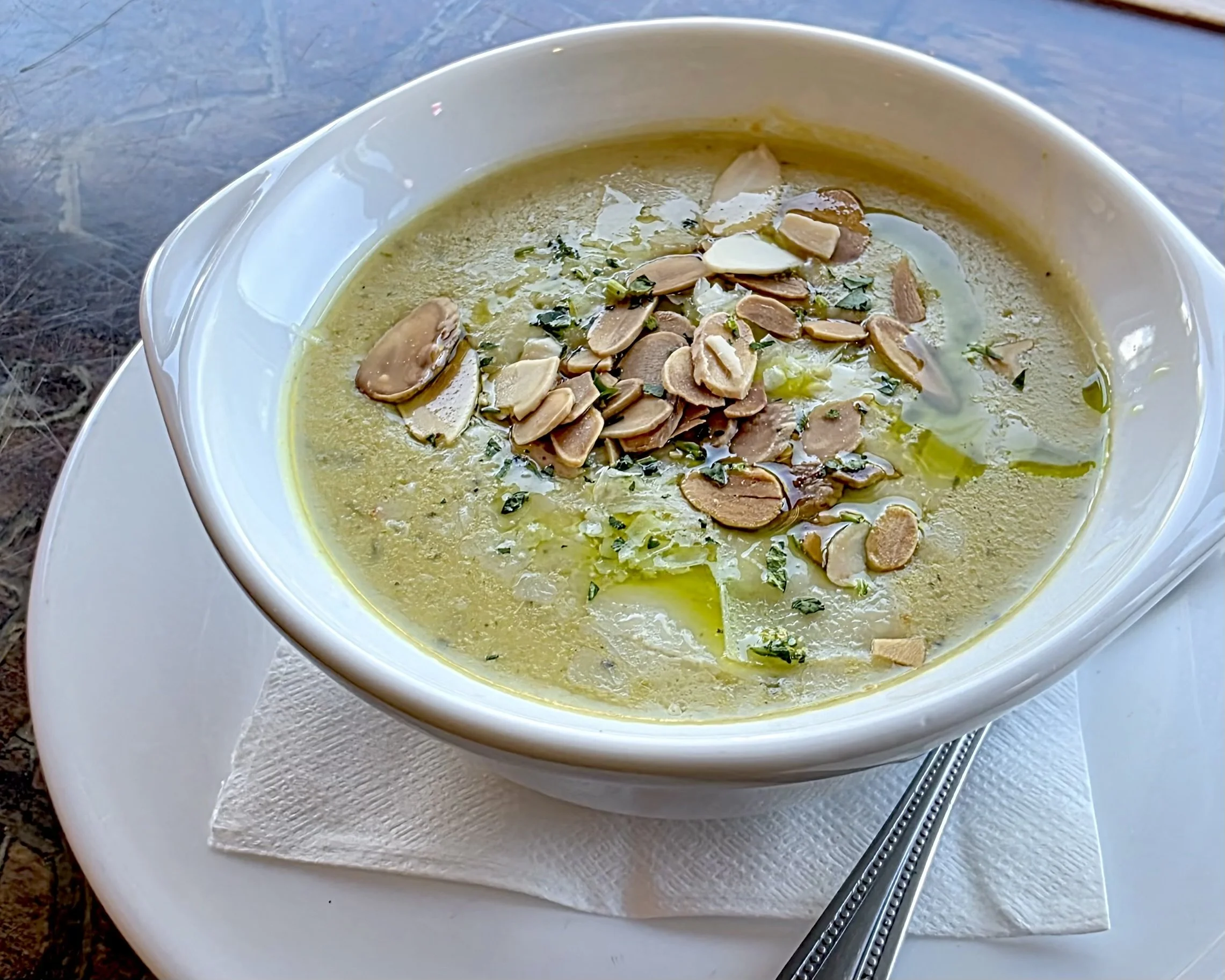 cup of piping hot asparagus soup topped with toasted almonds