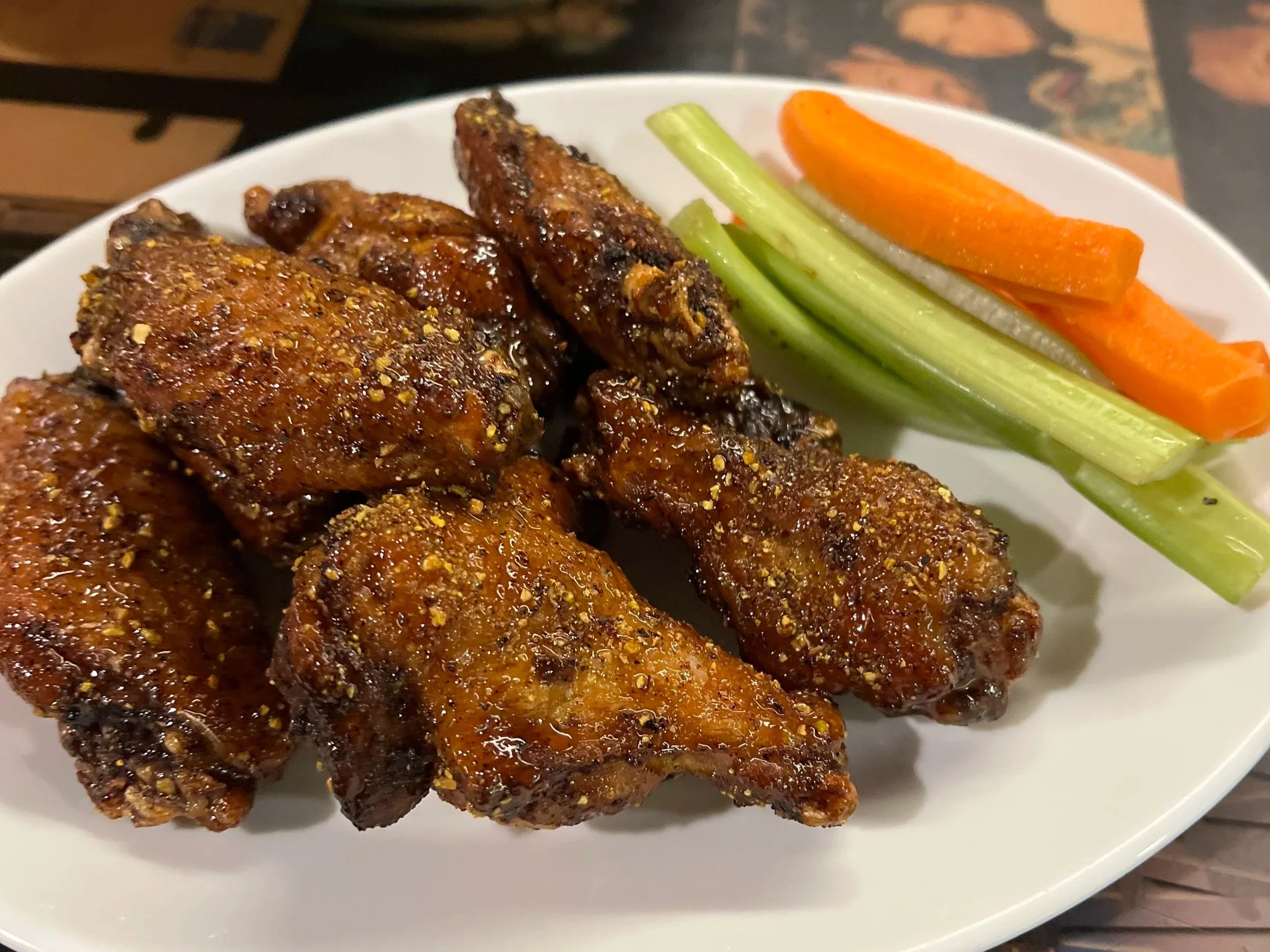 Lemon-pepper wings on a plate with carrots and celery
