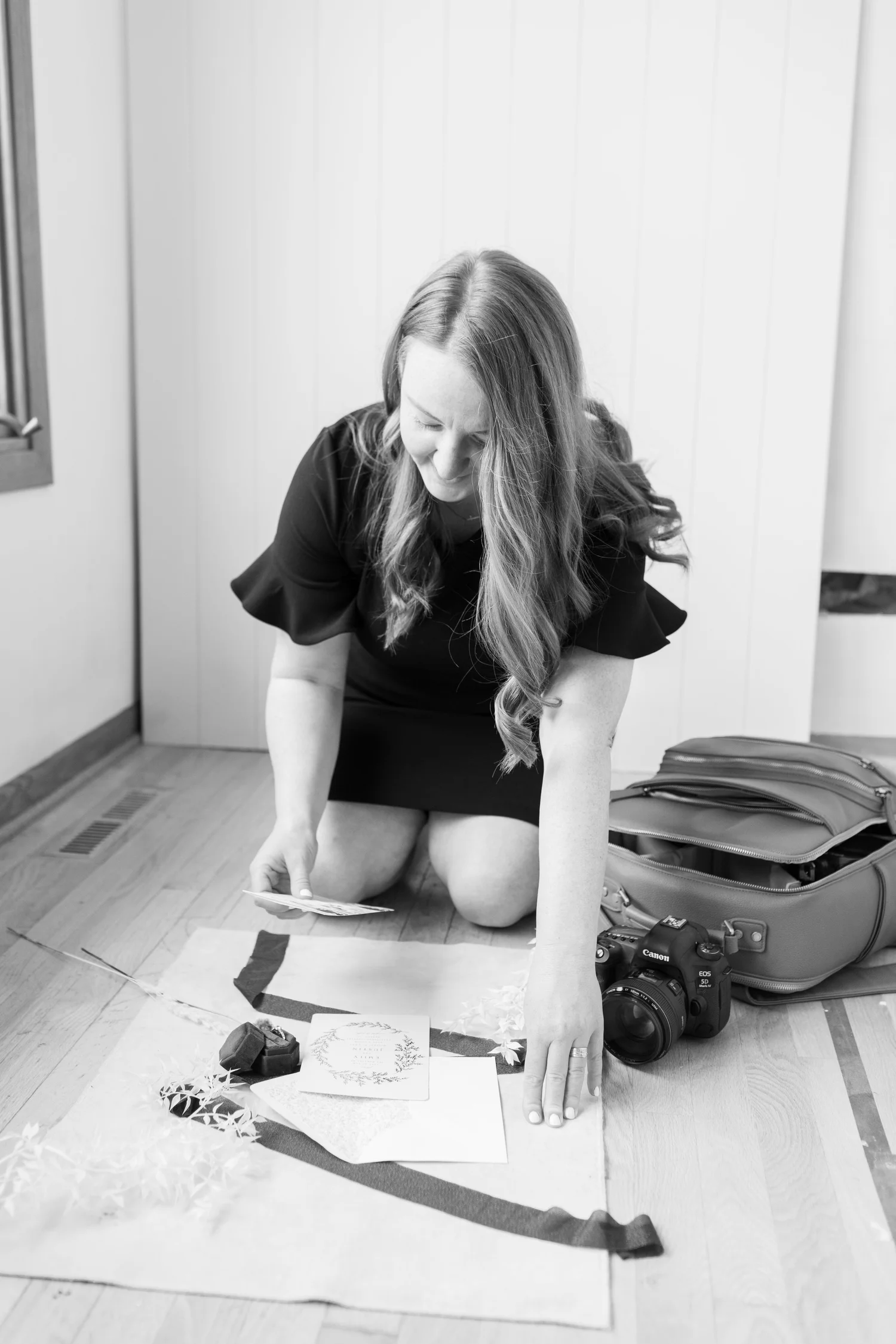 Elyse arranging wedding details beside her camera gear