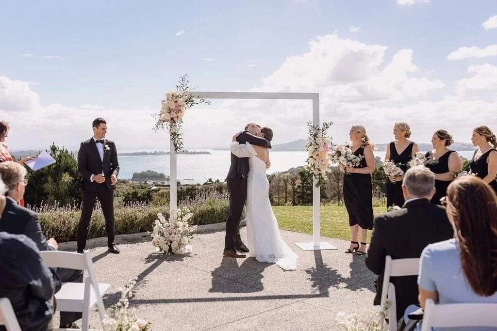 White wedding arbour decorated with blush and ivory flowers at Mudbrick Vineyard