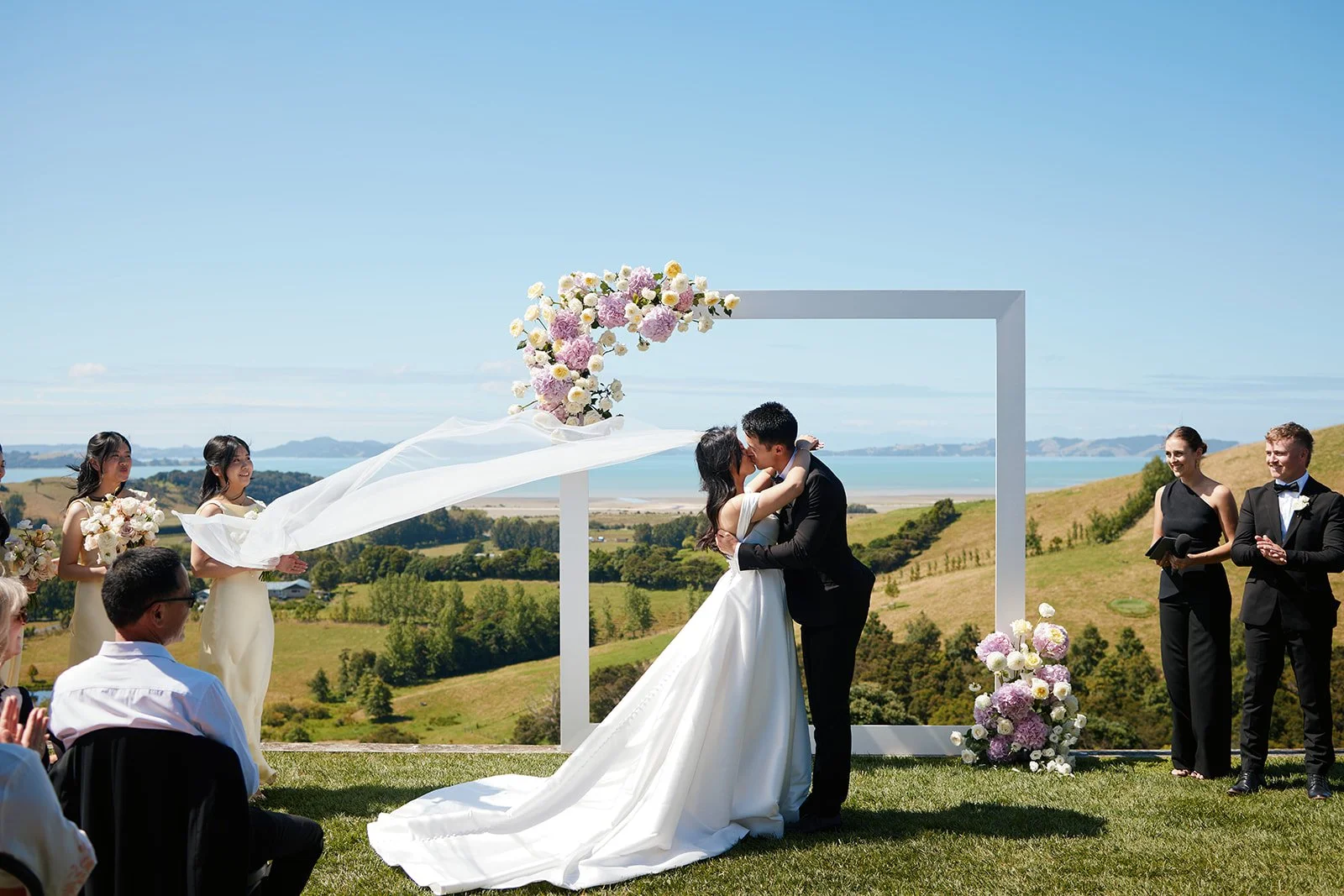 Pastel wedding flowers arranged on a modern white ceremony frame at Kauri Bay