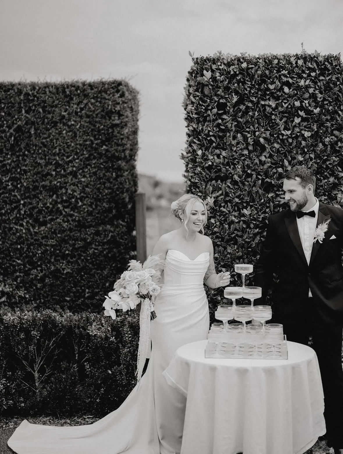 Bride and groom celebrating beside a champagne tower at Turanga Creek wedding in Auckland.
