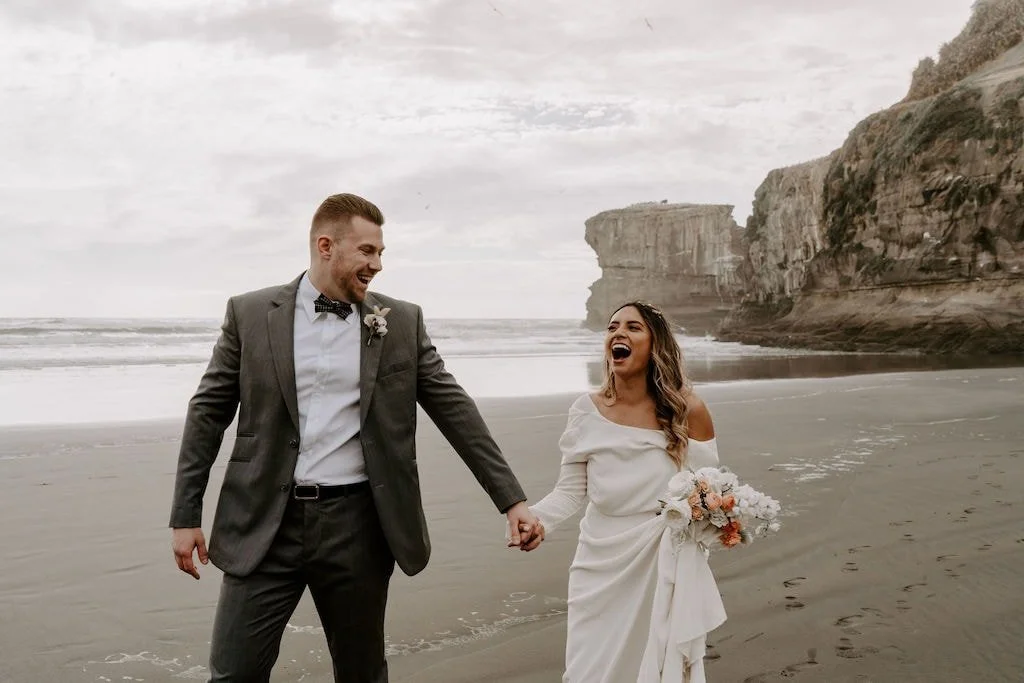 Bride and groom holding a romantic white and blush wedding bouquet during a West Coast New Zealand elopement.