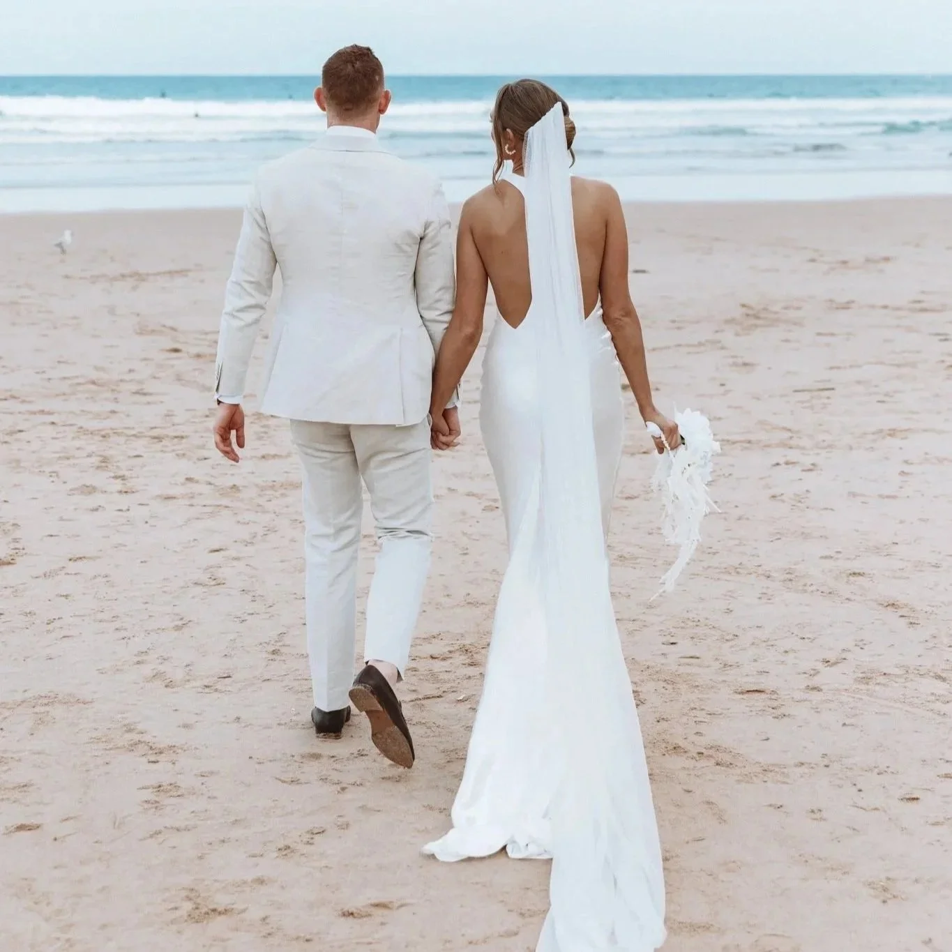 Couple in wedding clothing holding hands on beach